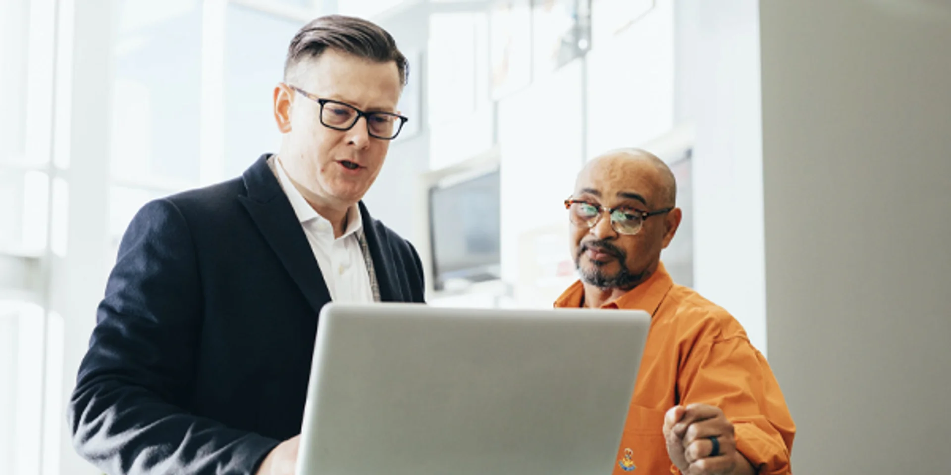 two men are looking at a laptop computer together .