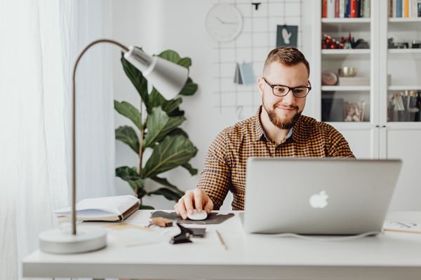 a man is sitting at a desk using a laptop computer .