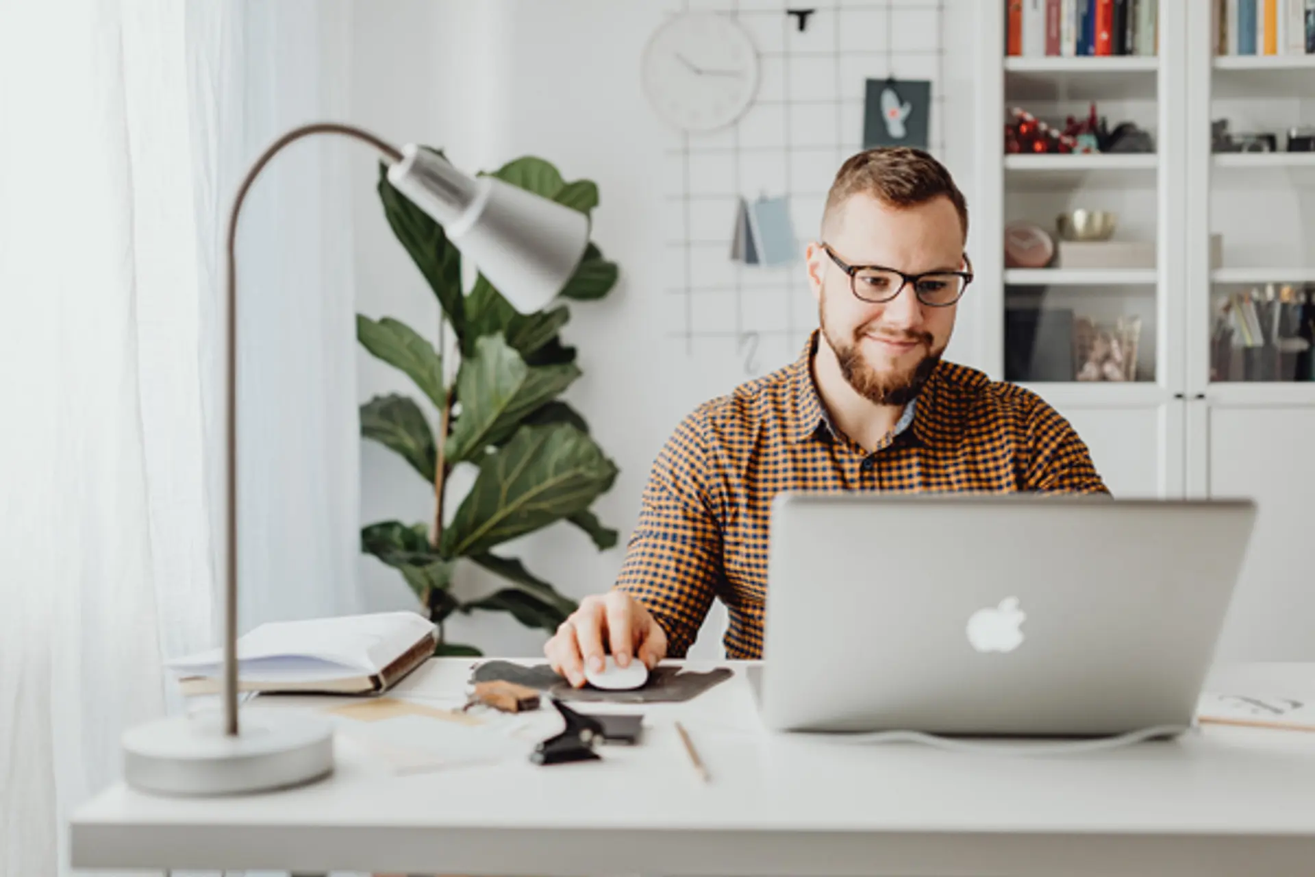 a man is sitting at a desk using a laptop computer .