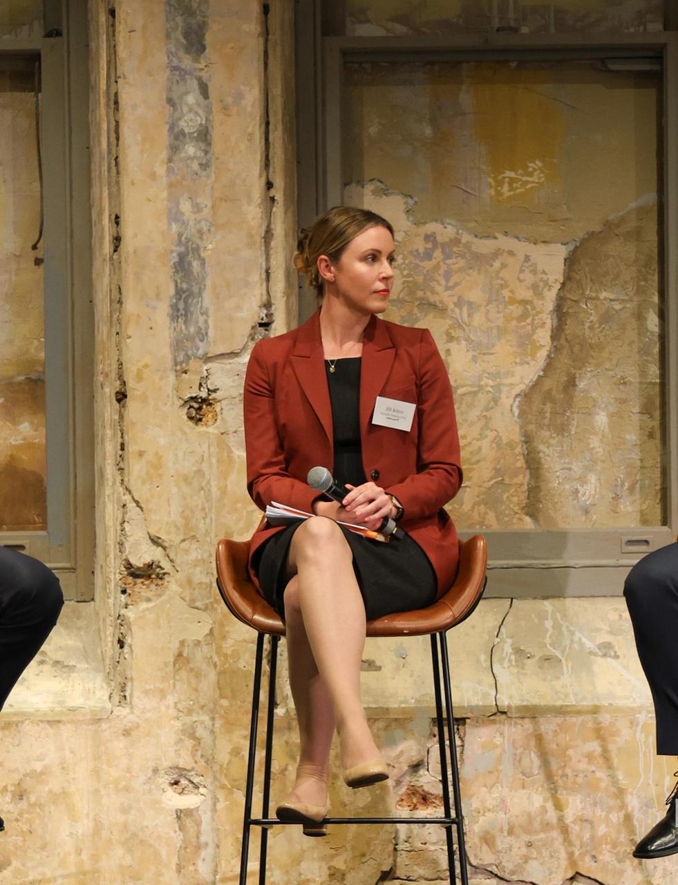 Three panelists, two men and one woman, seated with microphones.