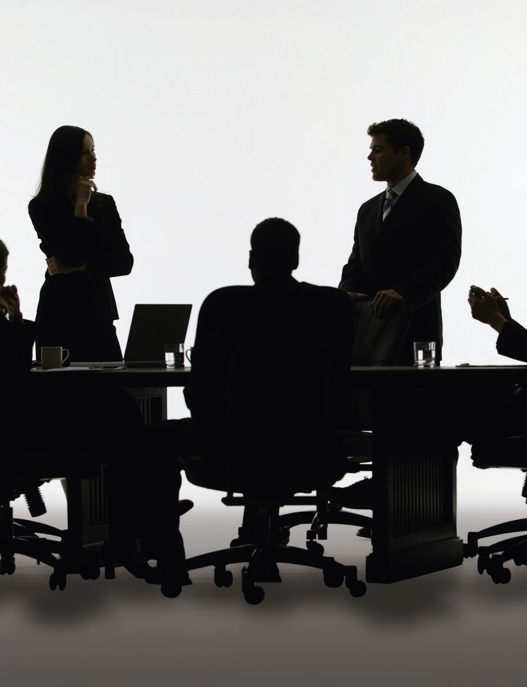 Five silhouetted business people at a meeting table.