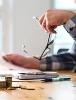 a man is sitting at a table with a calculator and stacks of coins .