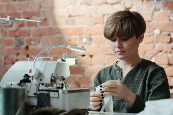 a woman is sitting at a table using a sewing machine .