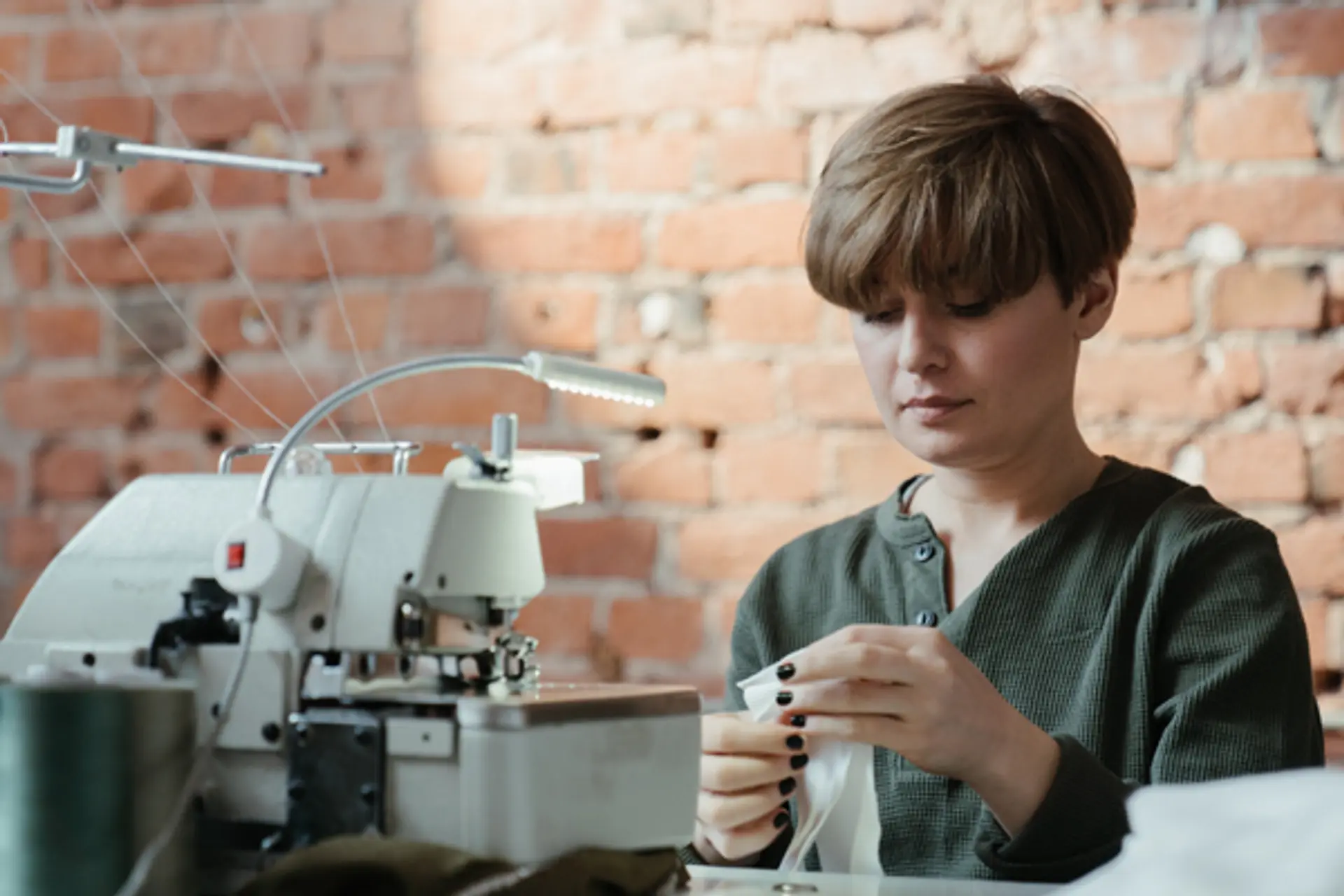 a woman is sitting at a table using a sewing machine .