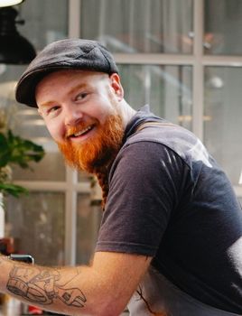 a man with a beard is cleaning a coffee machine in a cafe .
