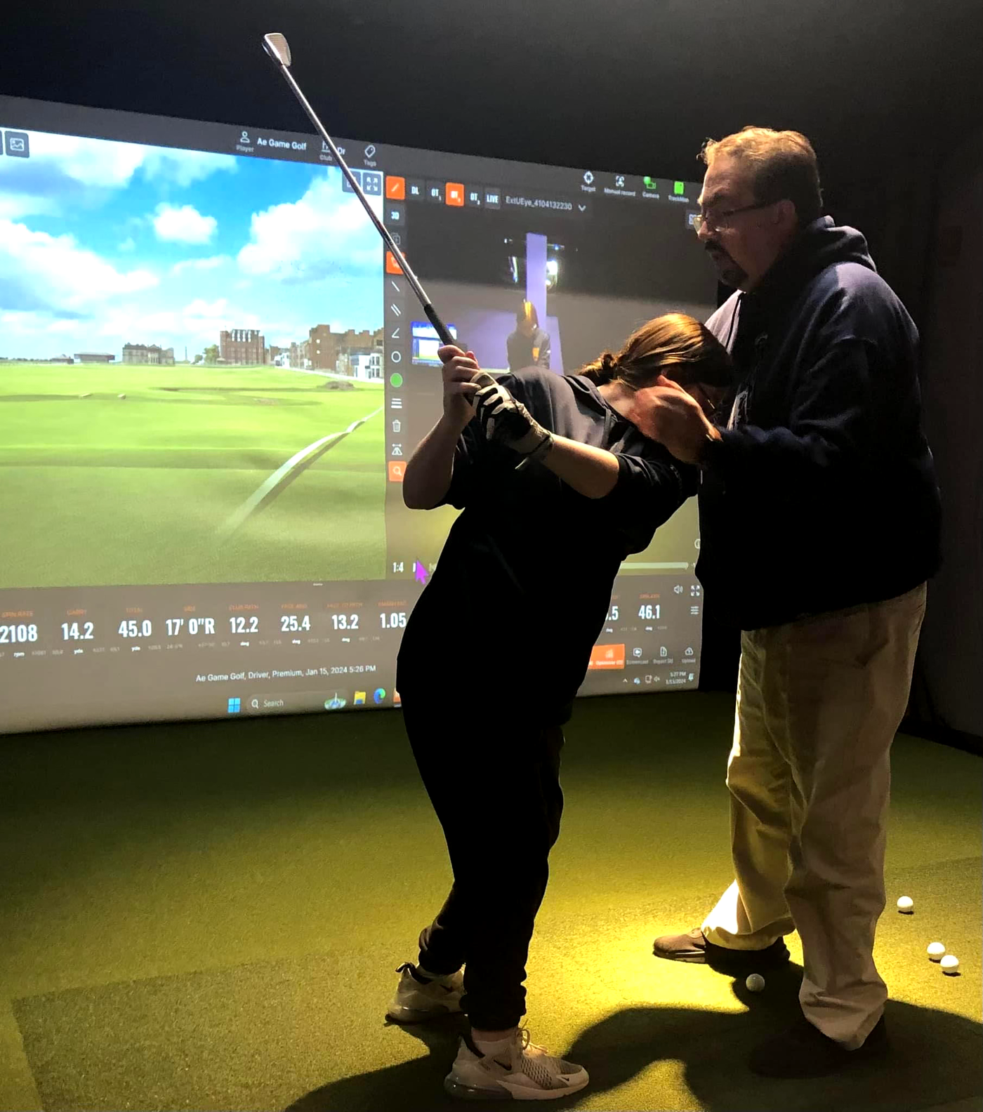 Golf coach working with a student during an indoor lesson.