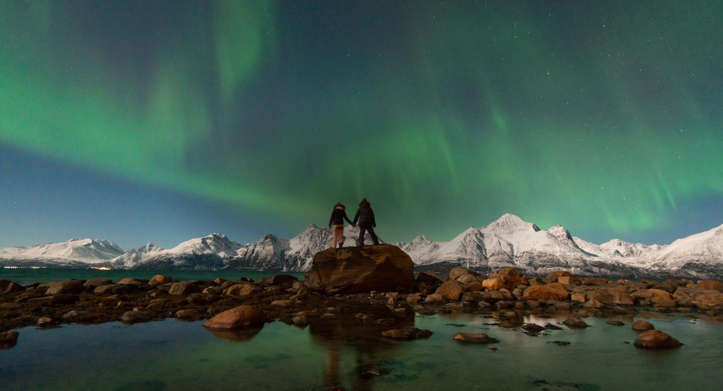 Honeymoon couple at the beach at Lyngen North experiencing the Northern Lights