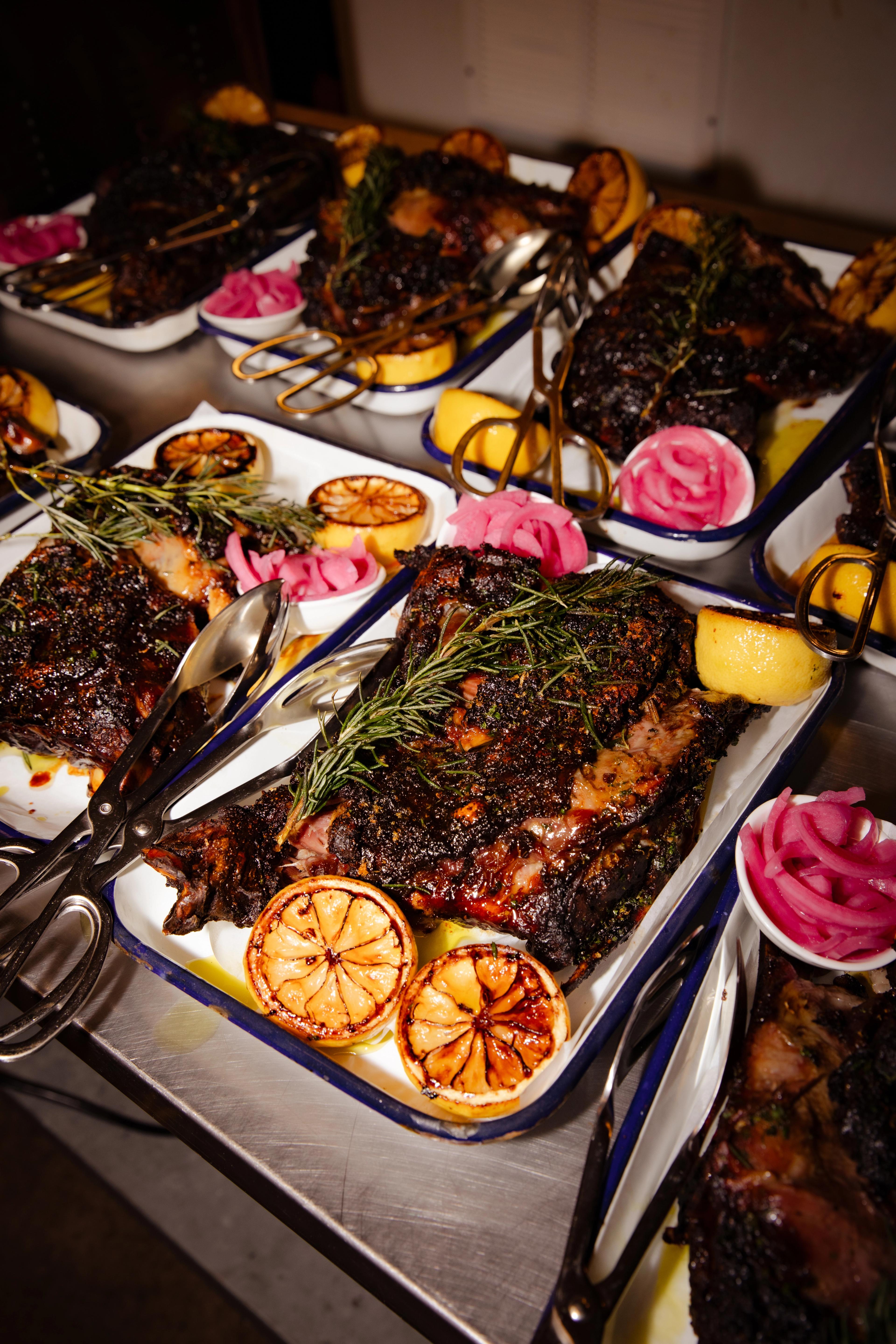 Tinsel hangs from the ceiling of a rustic industrial event space while a crowd of people dance to music played by a live DJ