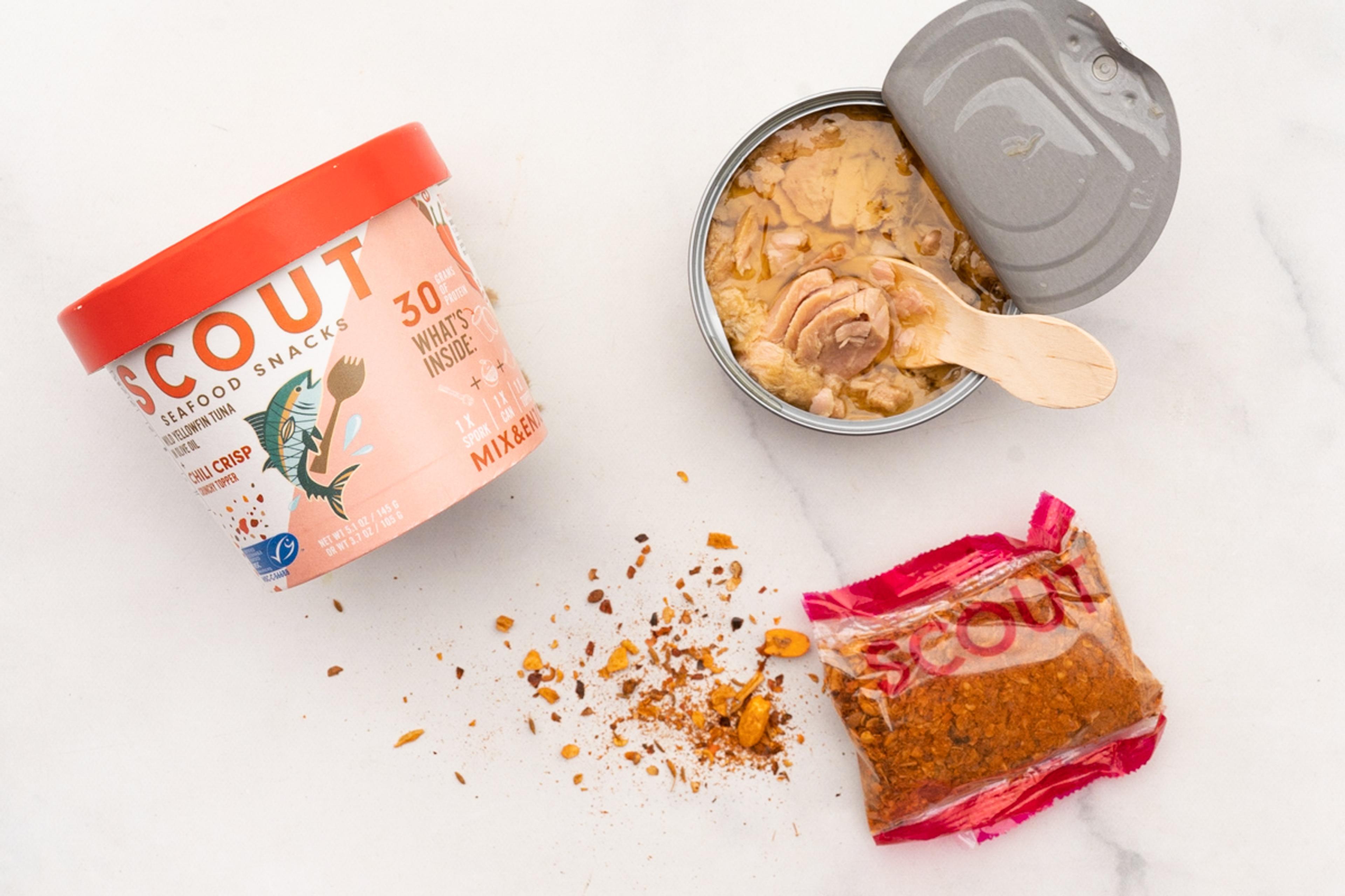 A open can of tuna sits next to a package of dried seasonings on a white marble counter