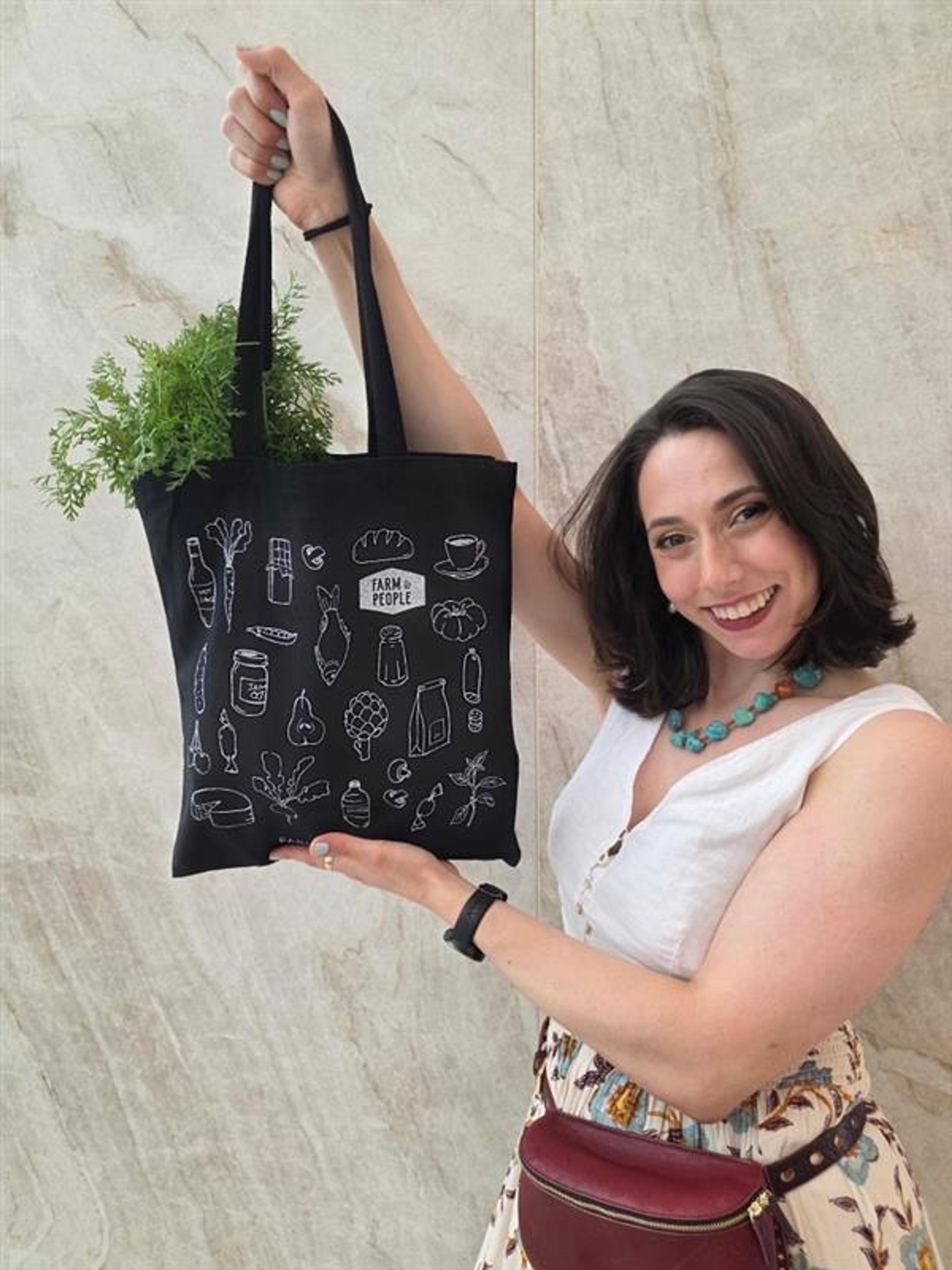 Long tables are set in preparation for a communal dinner beneath string lights in a rustic industrial event space