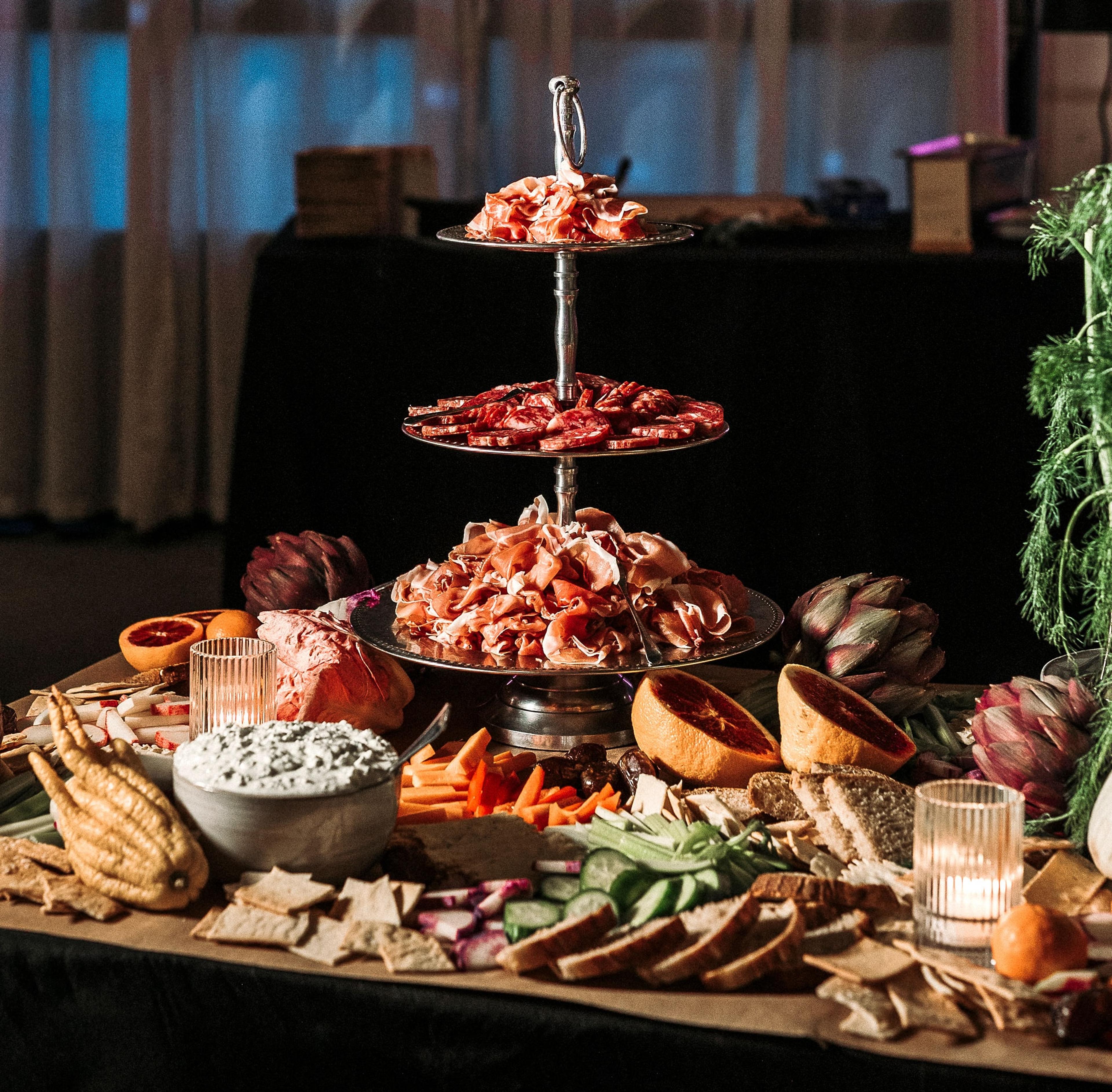 Tinsel hangs from the ceiling of a rustic industrial event space while a crowd of people dance to music played by a live DJ