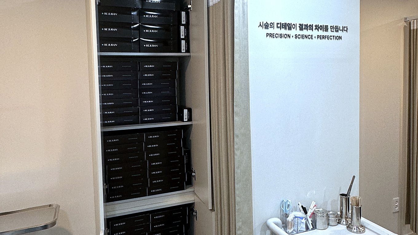 A treatment room with a wall slogan and genuine Rejuran kept in the storage cabinet