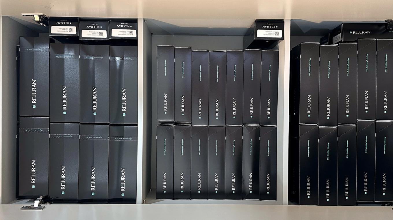 Genuine Rejuran boxes lined up in the cabinet, with QR codes and serial labels on the top of each box