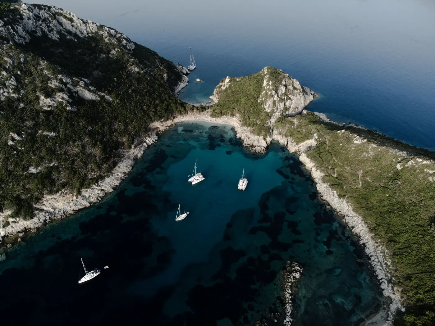 A catamaran and sailing yachts at anchor in the twin bay of Porto Timoni, Corfu, Greek islands, seen from above (photo urtimud.89, Pexels 9155413)
