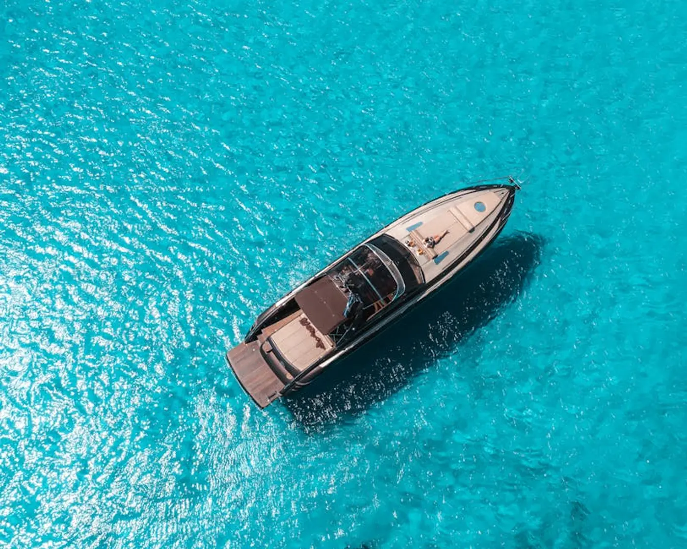 Aerial view of a private crewed yacht in the crystal-clear waters off Mykonos — Greek island yacht charter 2026