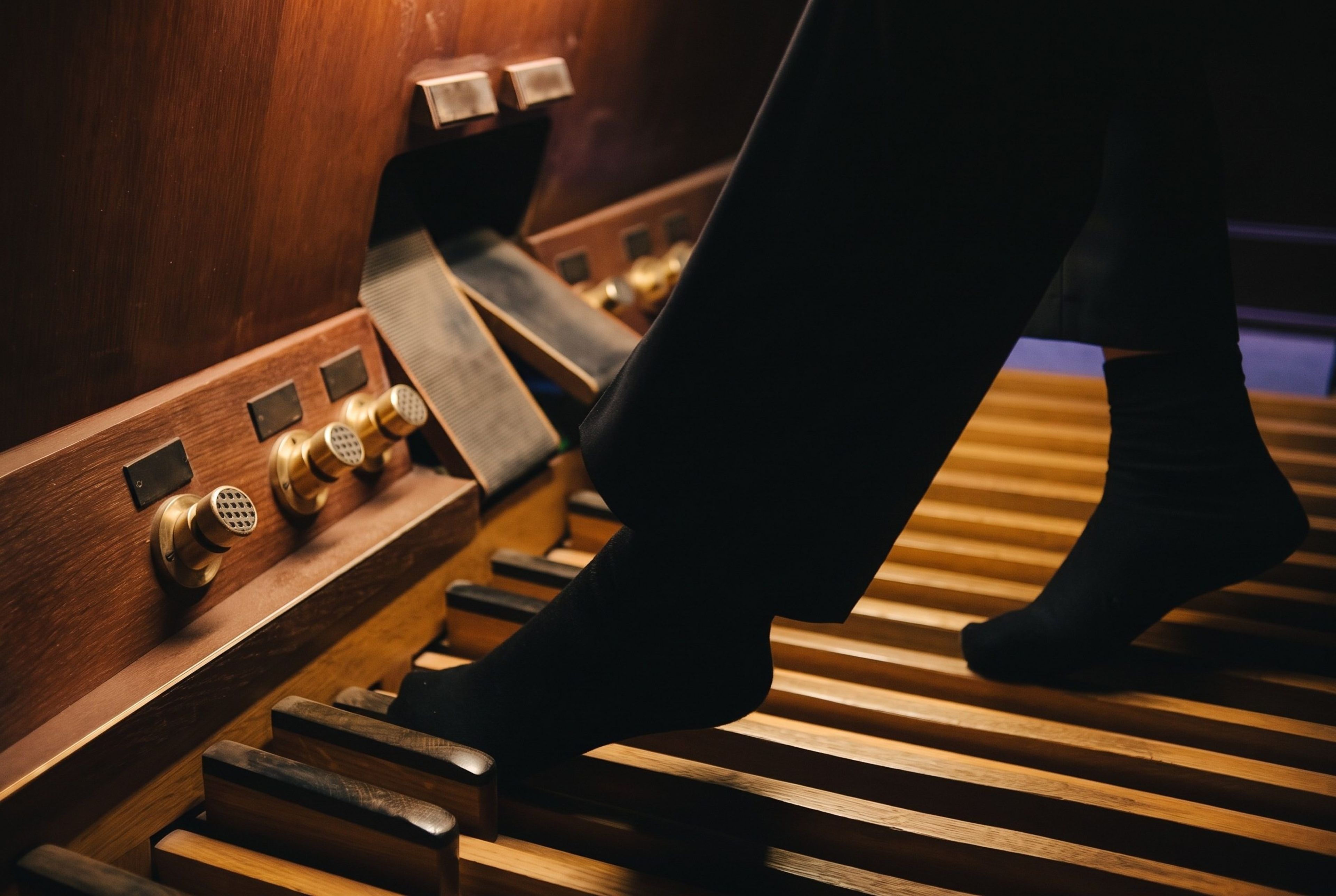 Stopy organisty na drewnianej klawiaturze pedałowej, mosiężne przyciski