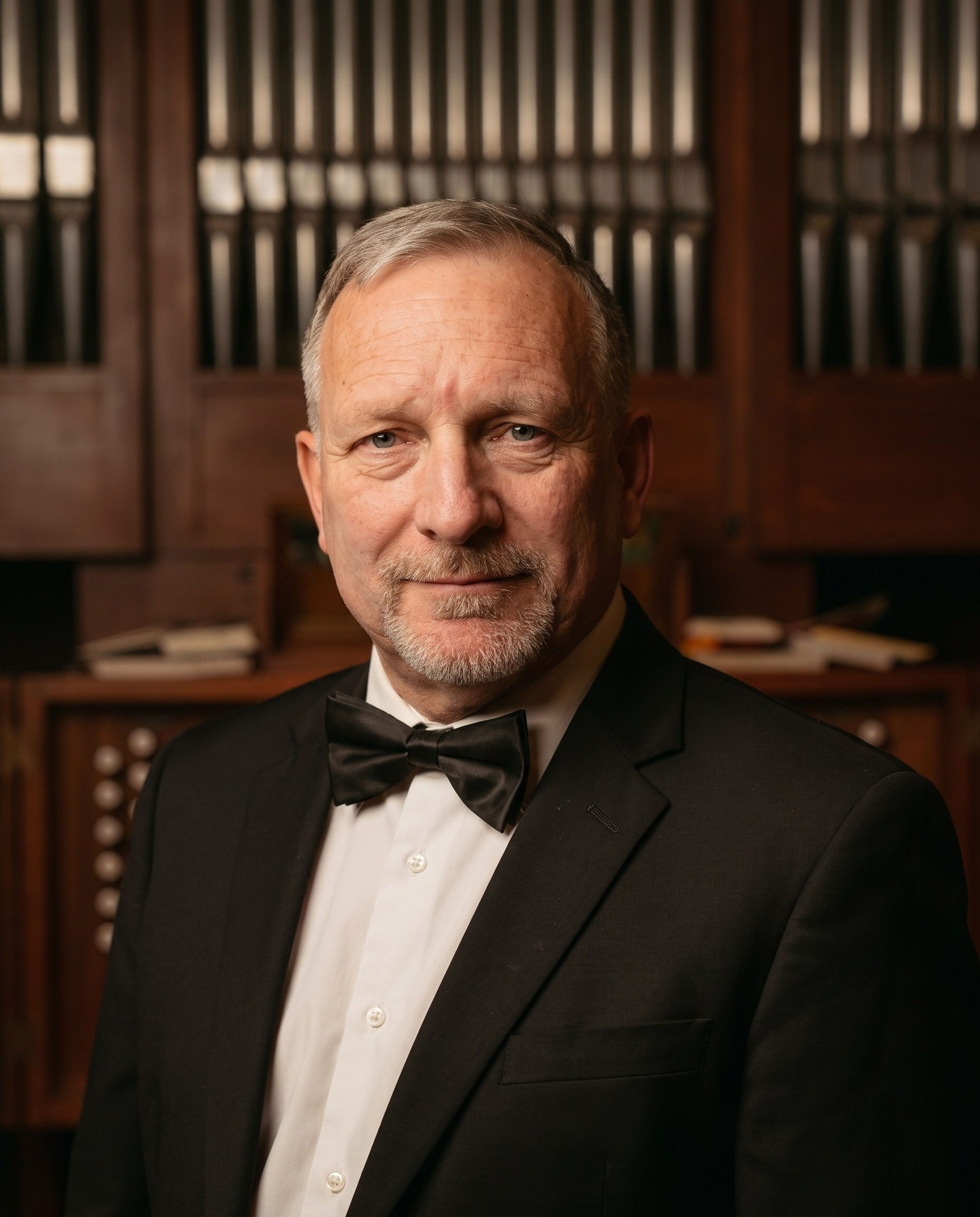 Portret Jana Kępińskiego we fraku na tle drewnianej szafy organowej z piszczałkami