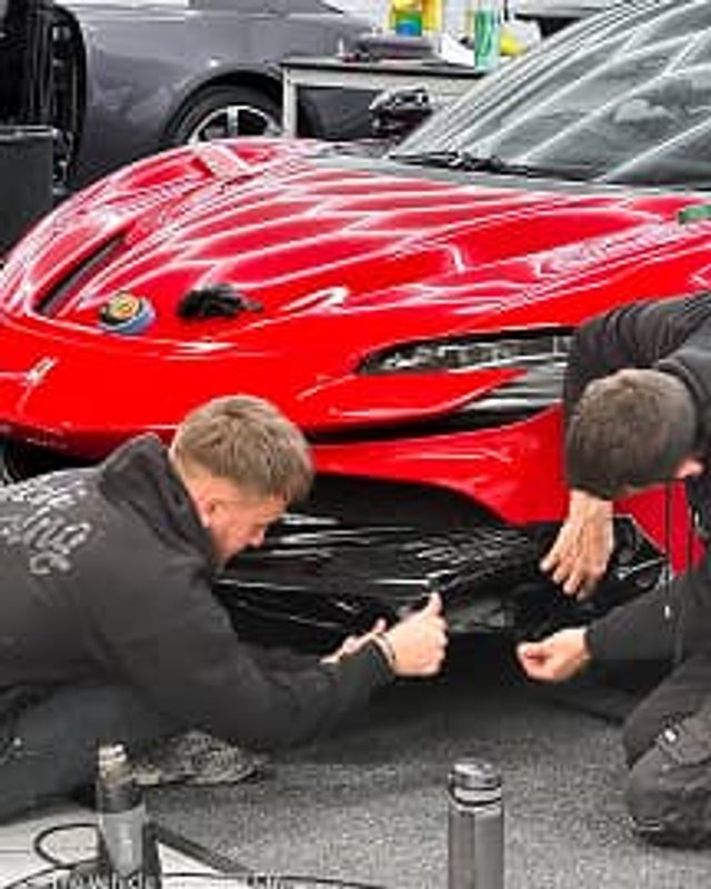 Two technicians meticulously applying PPF