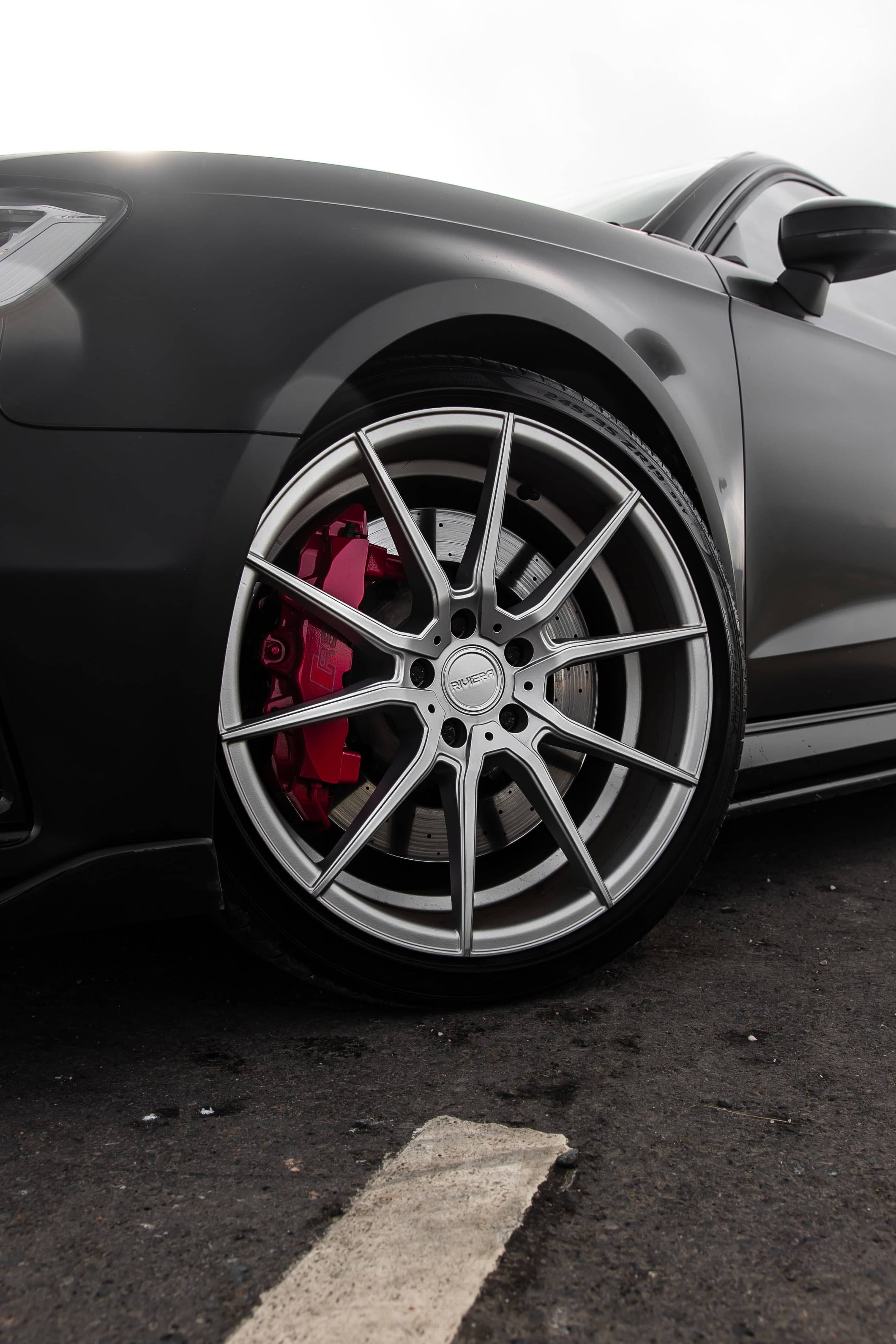A custom Forge Audi RS3 features silver multi-spoke Riviera wheels and bright red brake calipers against a dark matte finish.
