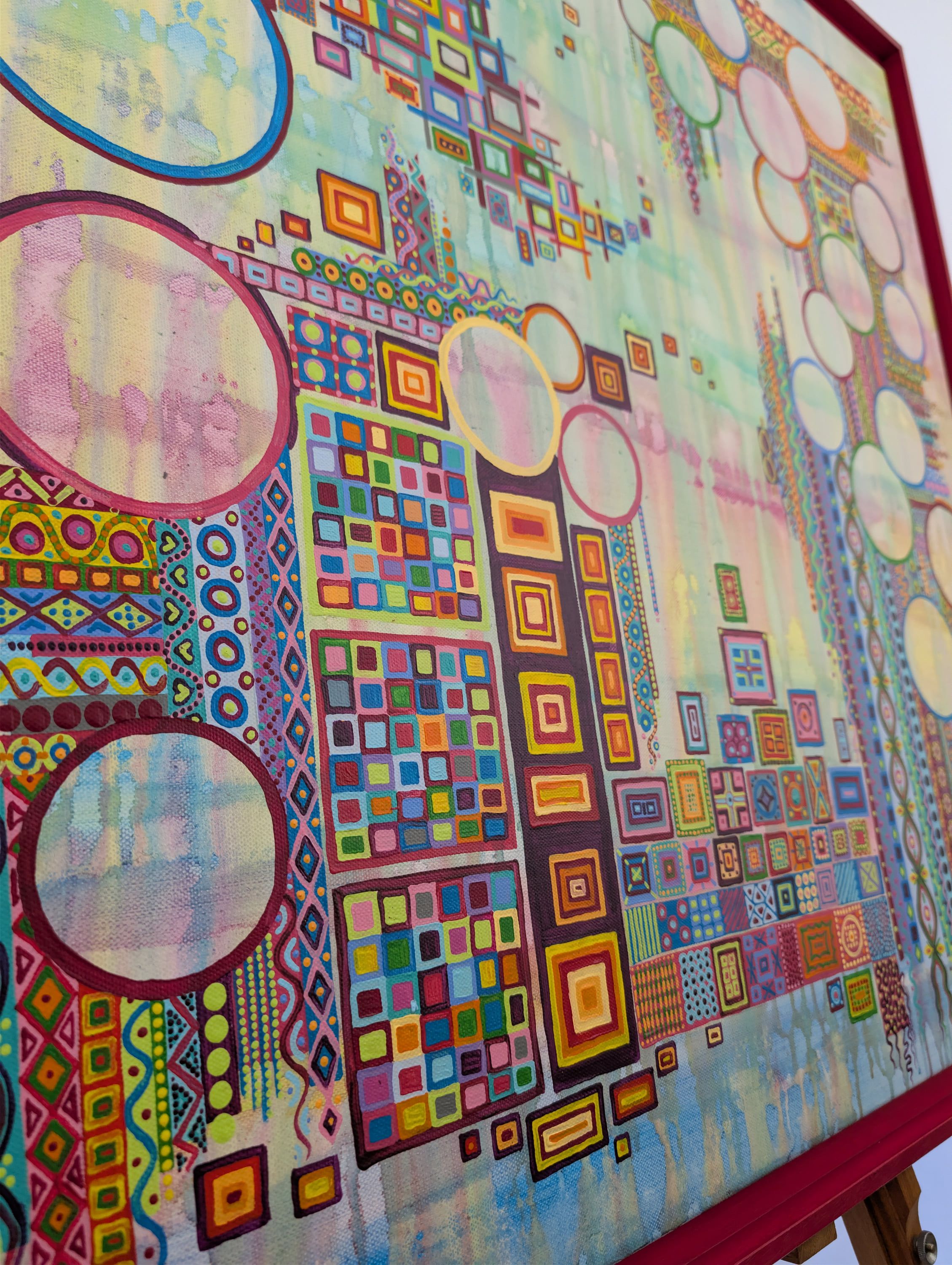 Détail vibrant d'une Toile acrylique de Caroline Pons, mêlant motifs géométriques, cercles colorés et textures pointillistes sur fond abstrait rose et bleu.