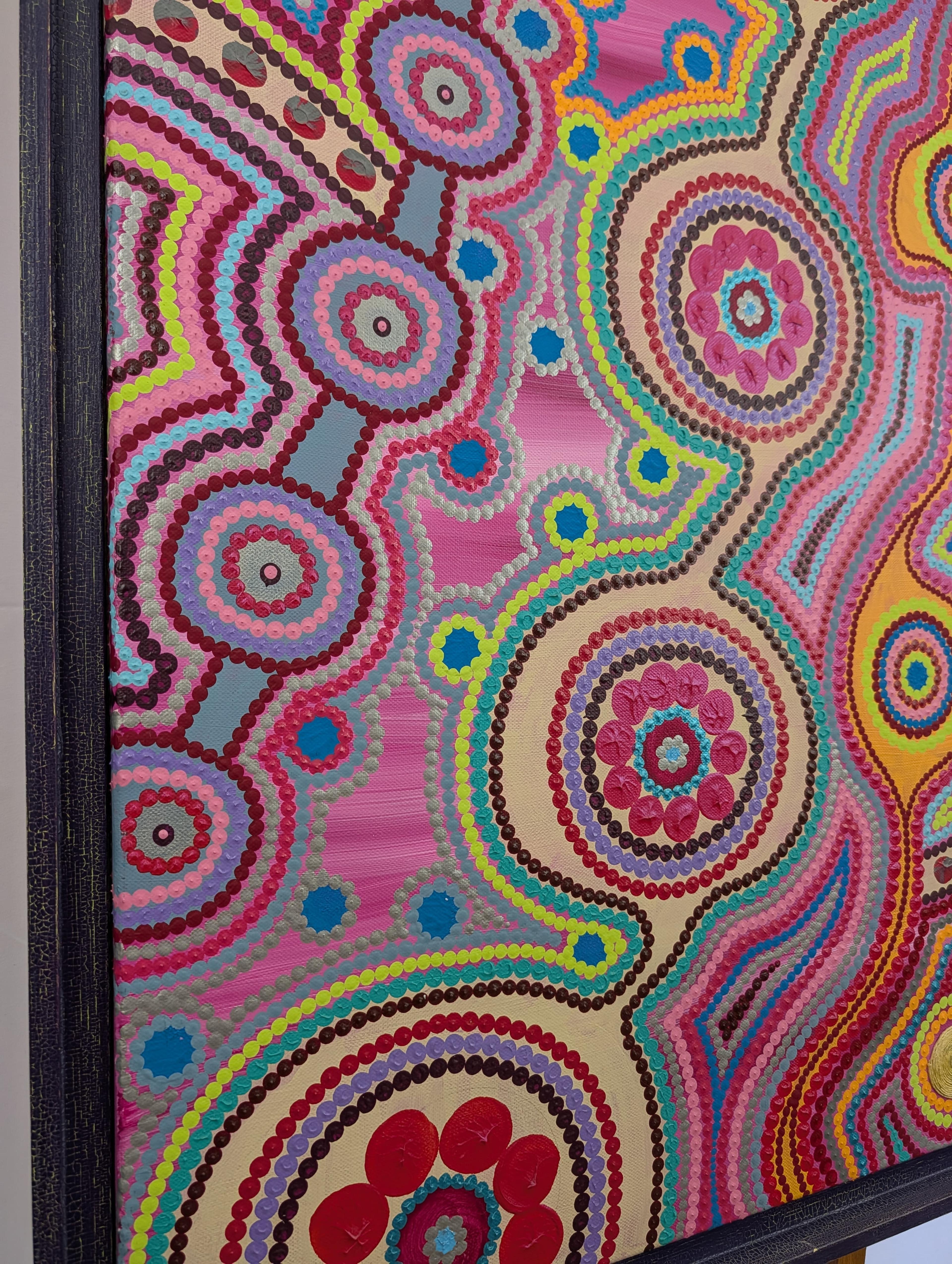 Détail vibrant d'une toile acrylique de Caroline Pons, motifs circulaires et lignes ondulées multicolores en pointillisme, inspirés de l'Art aborigène contemporain, dans un cadre texturé.