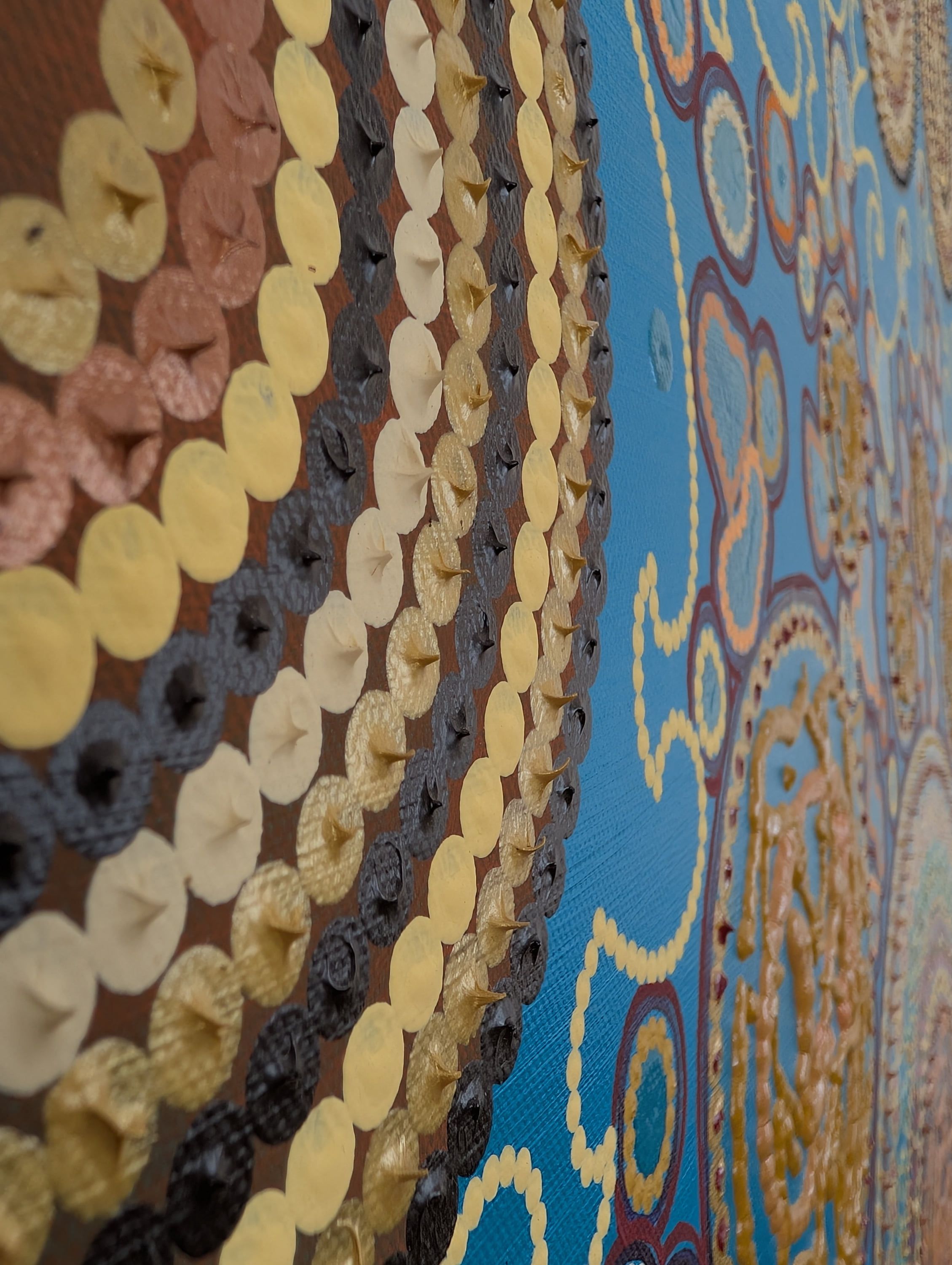 Textured acrylic canvas detail by Caroline Pons, Where do I live, featuring raised gold and brown dots, alongside vibrant blue and orange circular patterns on a blue base.