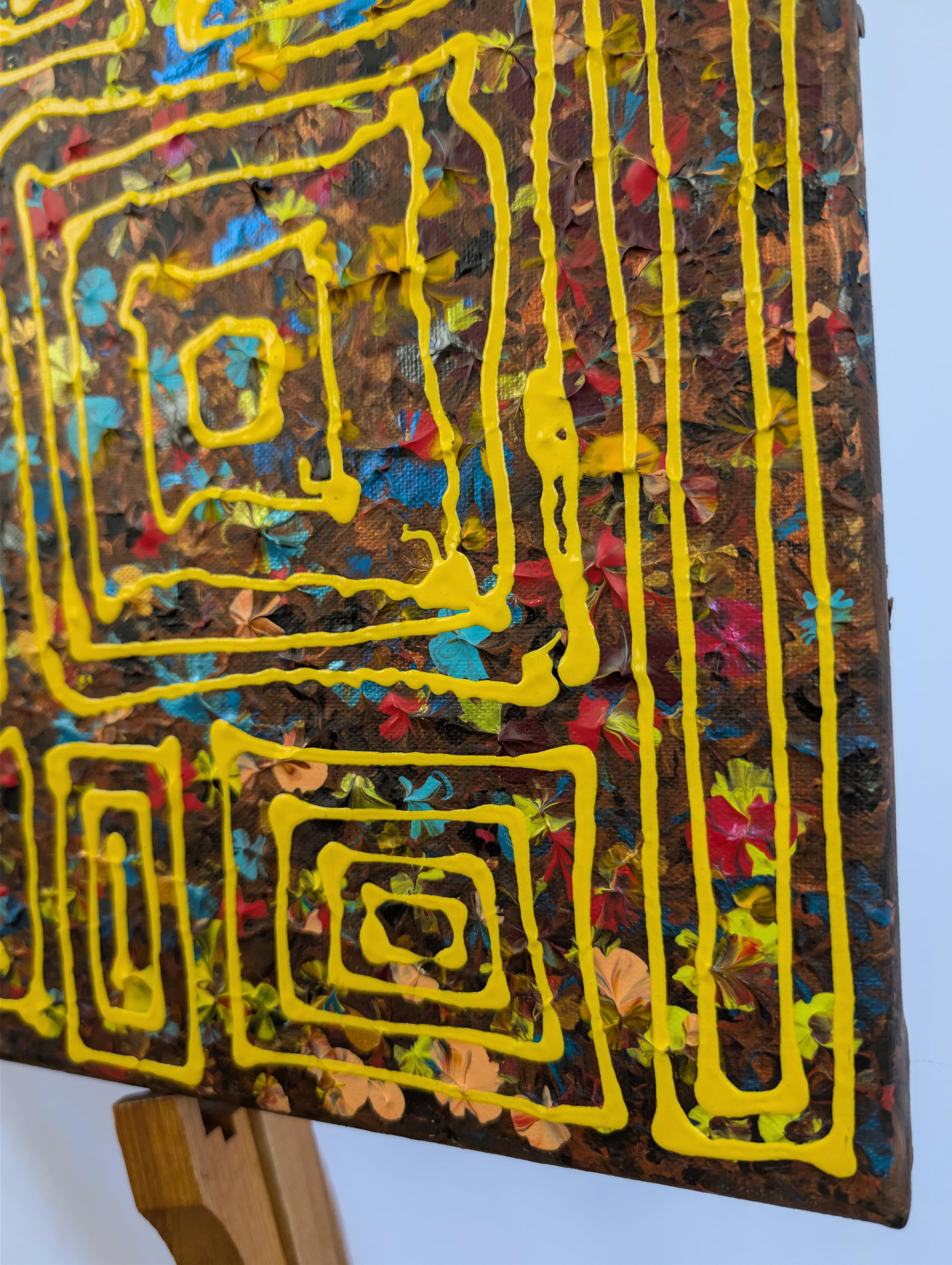 Détail texturé de la Toile acrylique 'Carrés nomades' de Caroline Pons. Lignes jaunes épaisses, carrés et rayures sur fond pointilliste vibrant (bleu, rouge, ocre).