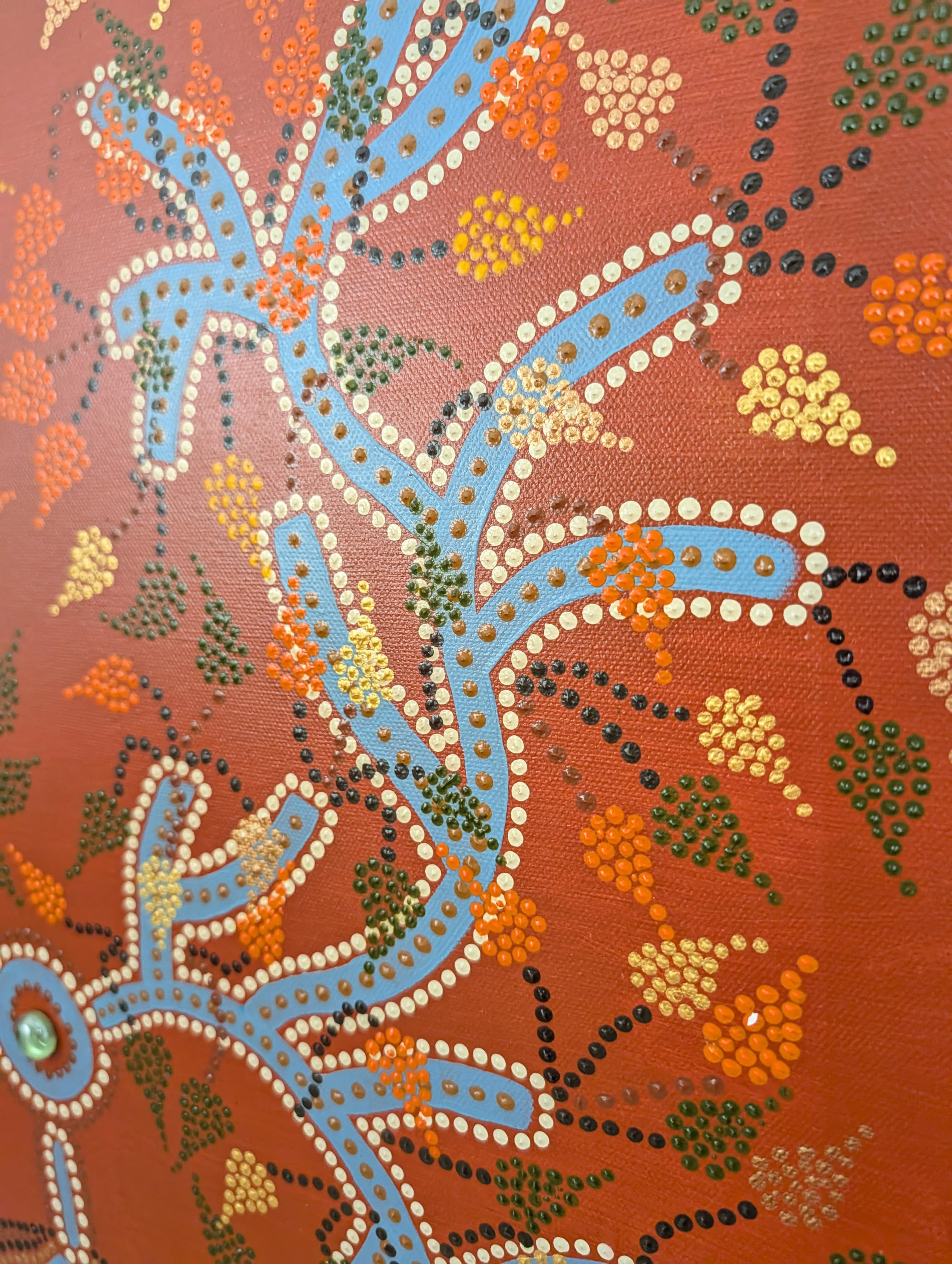 Detail of Caroline Pons' "L'arbre", original artwork. Blue, orange, gold, green dots on textured terracotta canvas, abstract tree with green bead.