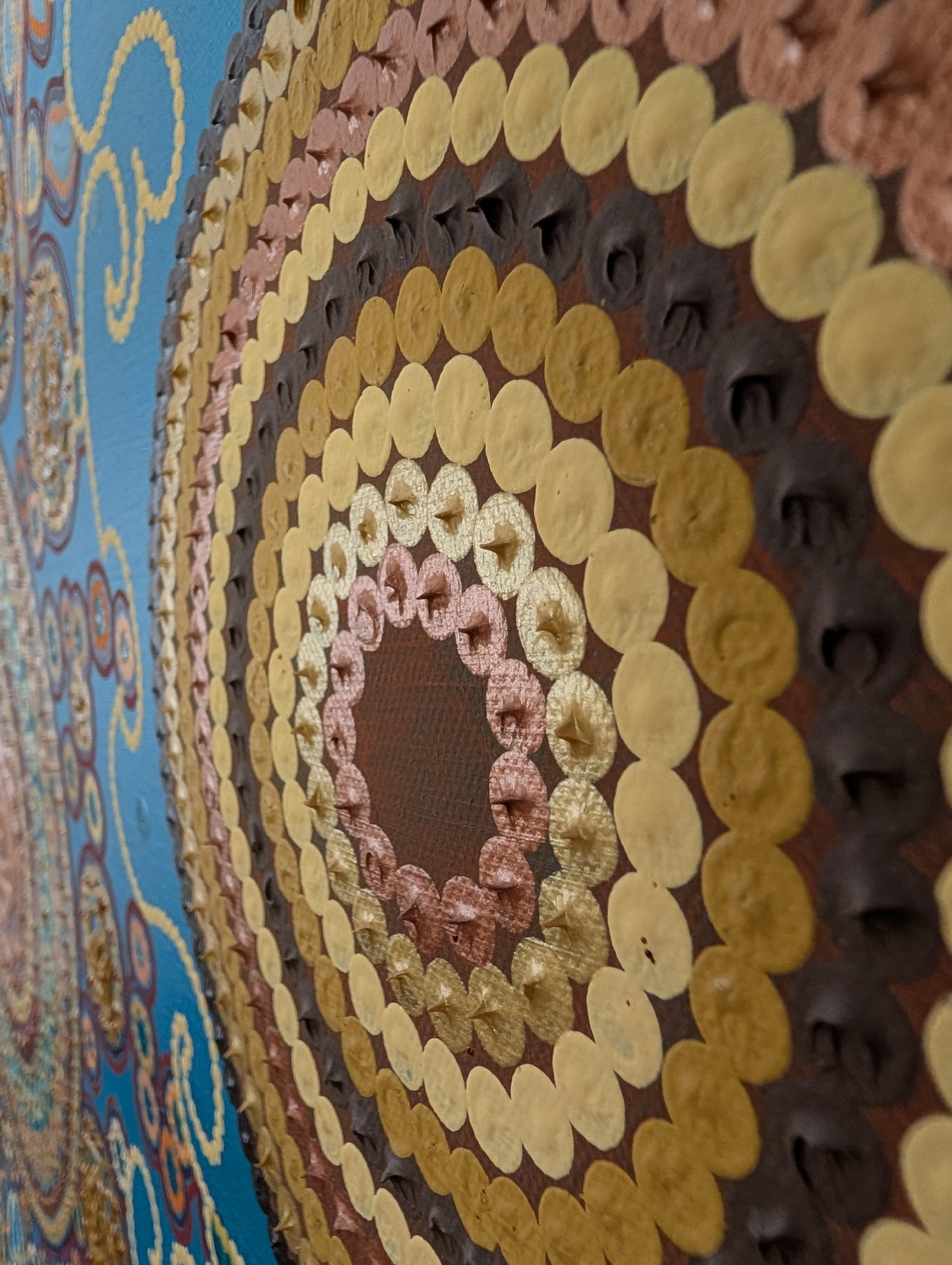 Textured close-up of Caroline Pons' 'Where do I live', showcasing Contemporary aboriginal-style art. Concentric circles of gold, copper, brown dots on teal.