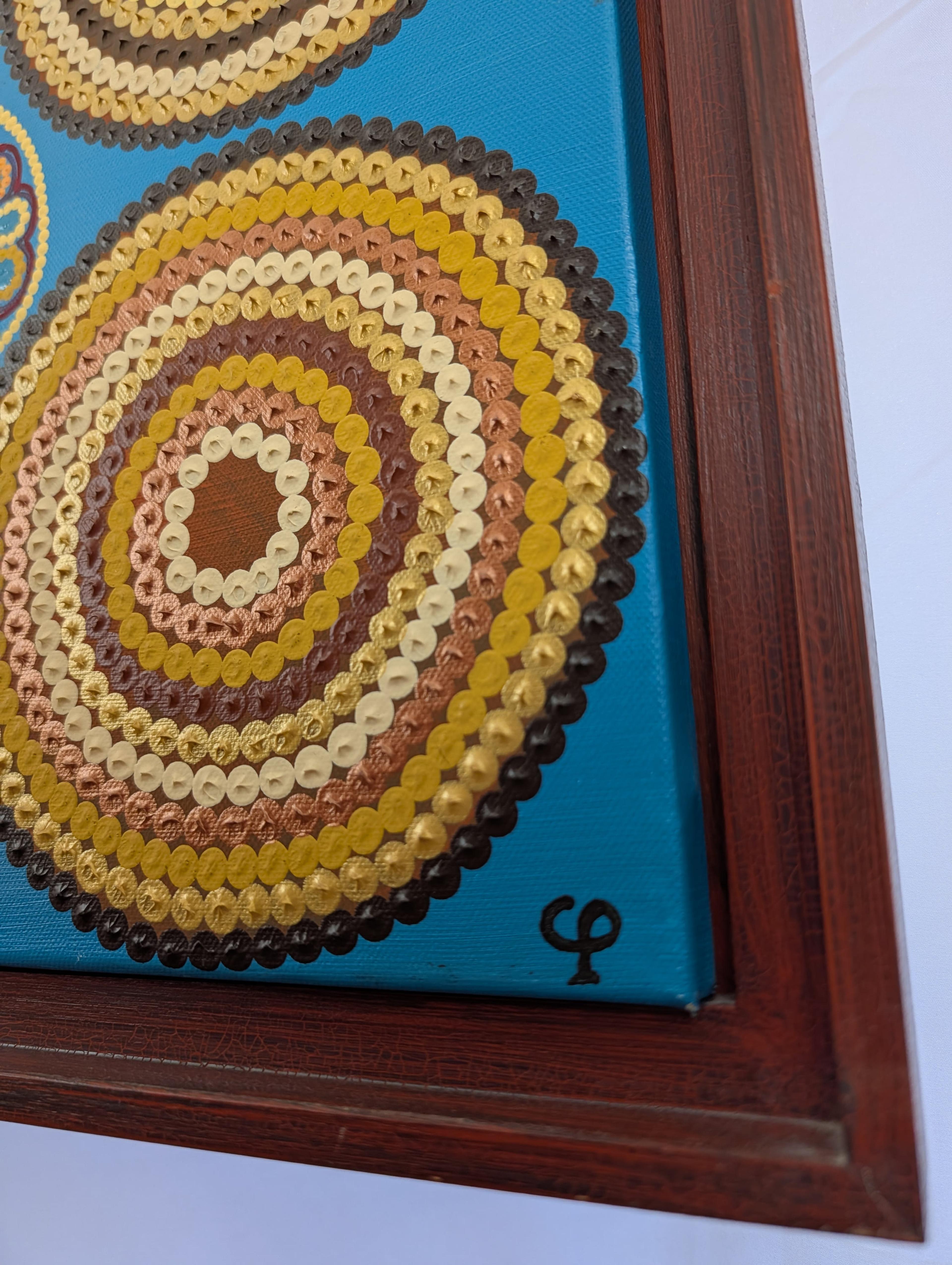 Close-up of Caroline Pons' "Where do I live", a Modern abstract painting. Textured gold, bronze, cream, brown dots form concentric circles on a vibrant turquoise canvas, framed in dark wood.