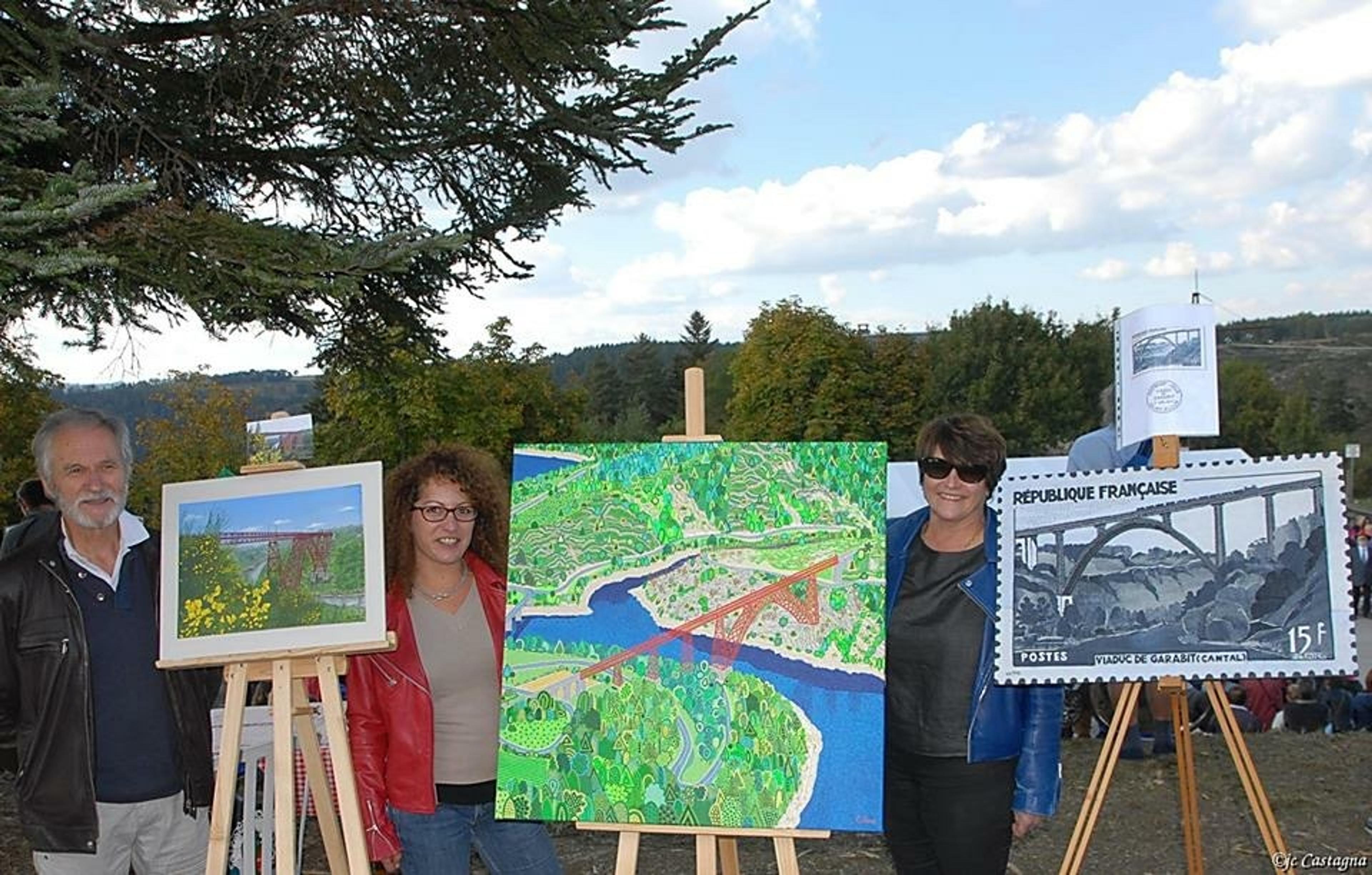 Caroline Pons beside her painting of the Garabit viaduct, between two other painters of the competition