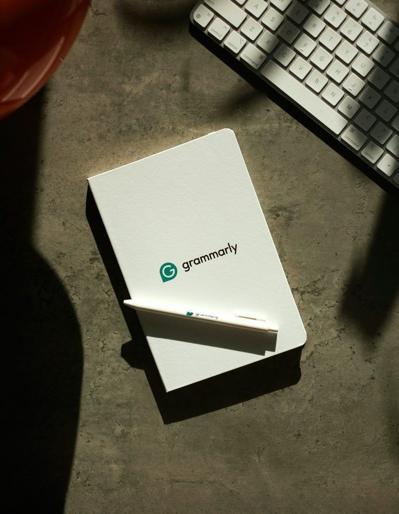 A Grammarly-branded notebook and pen resting on a desk beside a keyboard