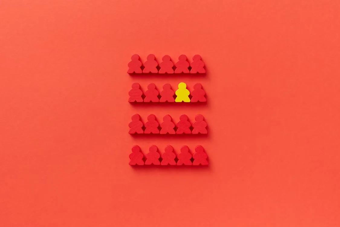 Rows of red figurine pieces with one yellow piece standing out among them