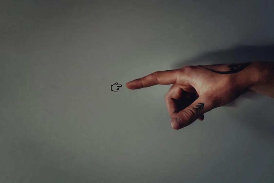 A hand with a tattoo pointing at a small cursor icon