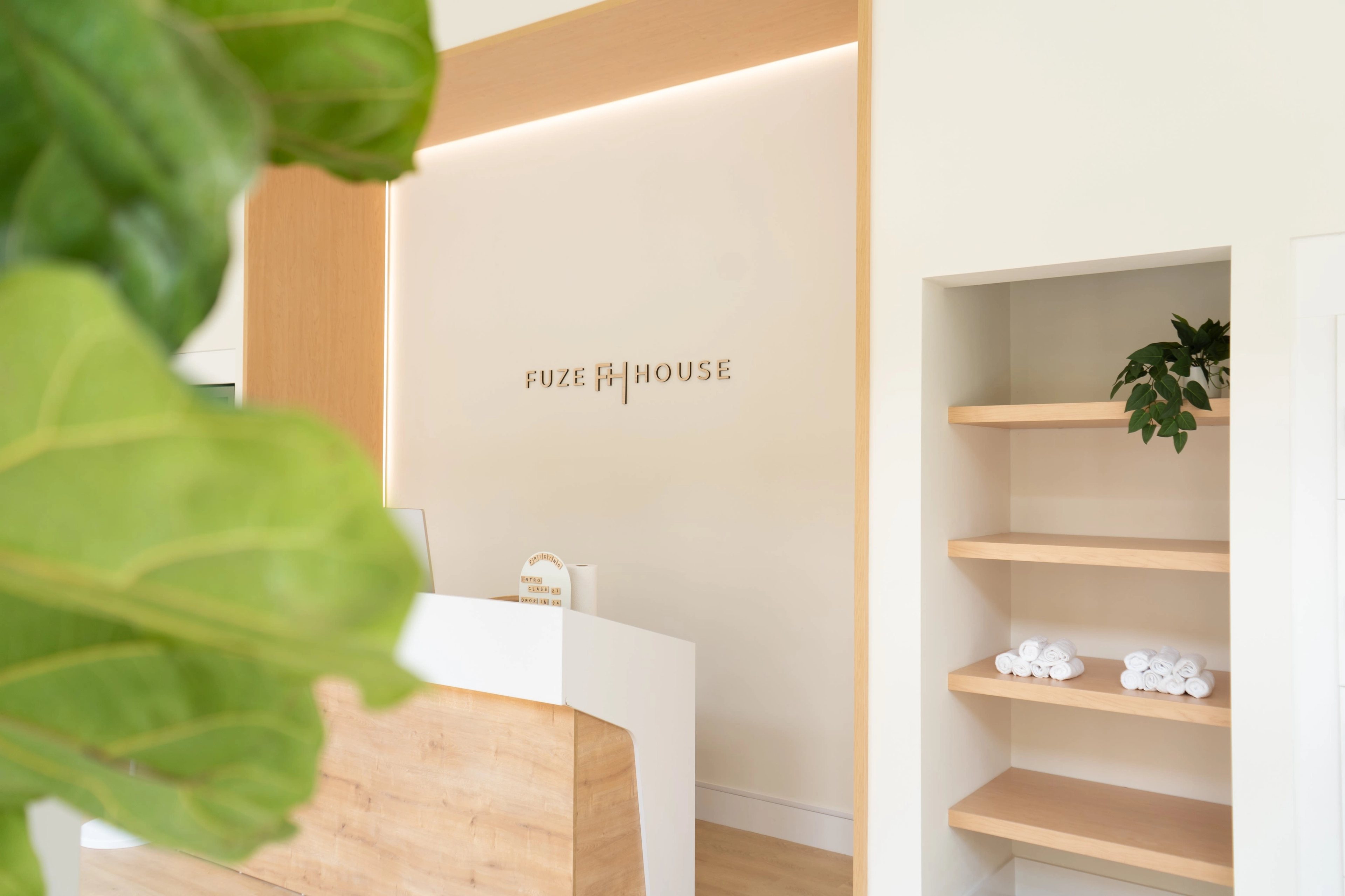 Light wood reception desk and open towel shelves in a Fuze House studio
