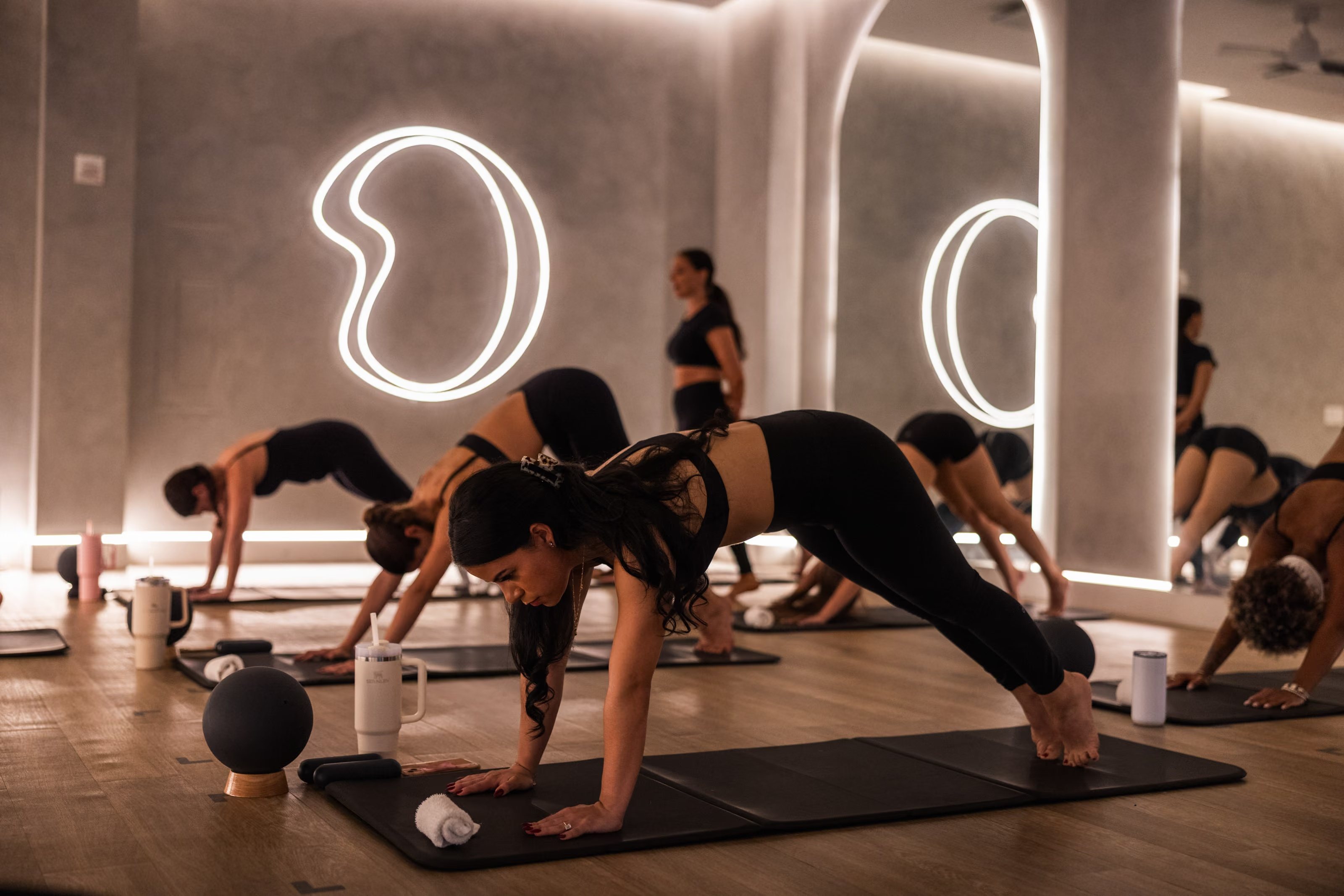 Mat Pilates class beneath illuminated arches at BODY Hot Pilates in Coral Gables