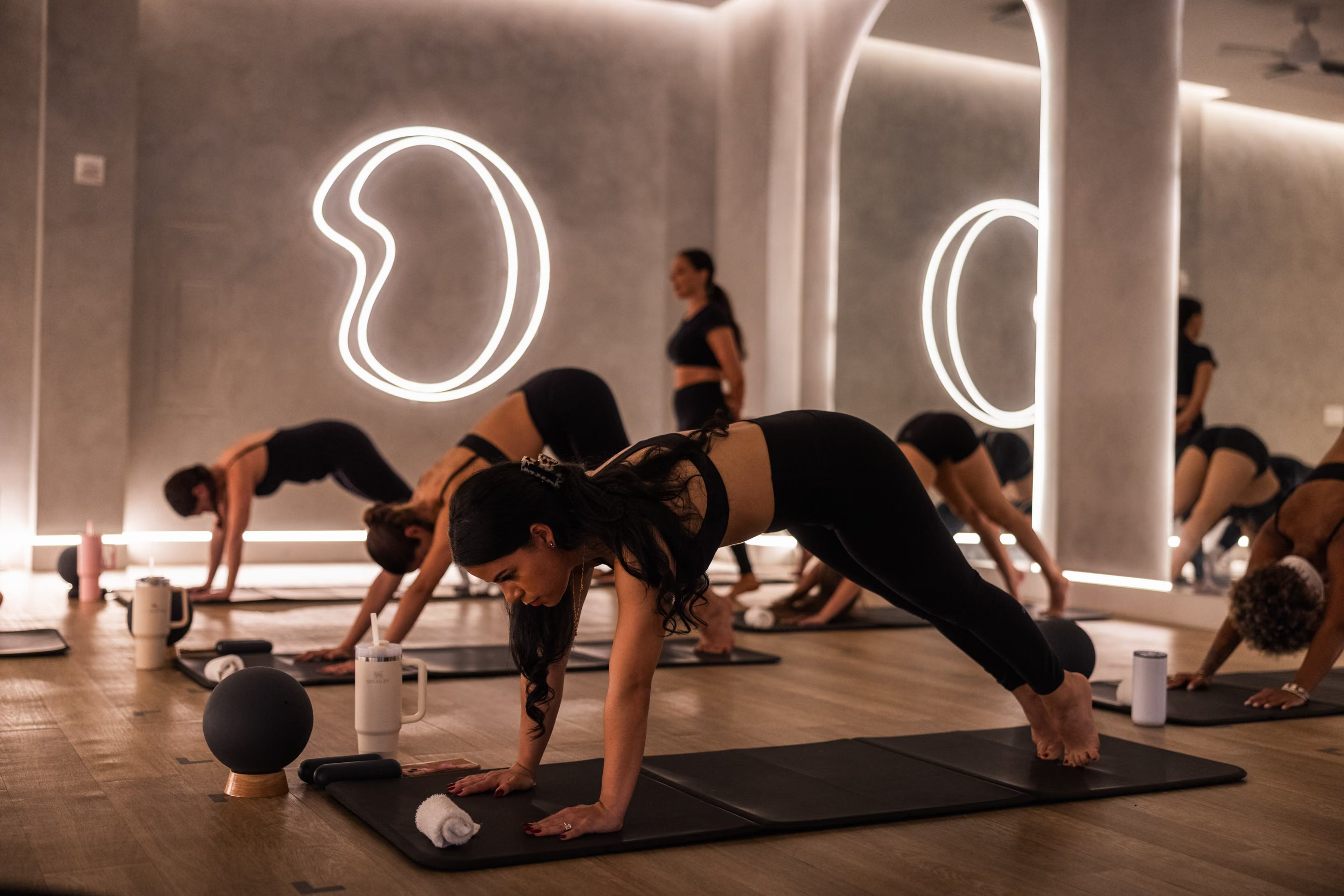 Mat Pilates class beneath illuminated arches at BODY Hot Pilates in Coral Gables