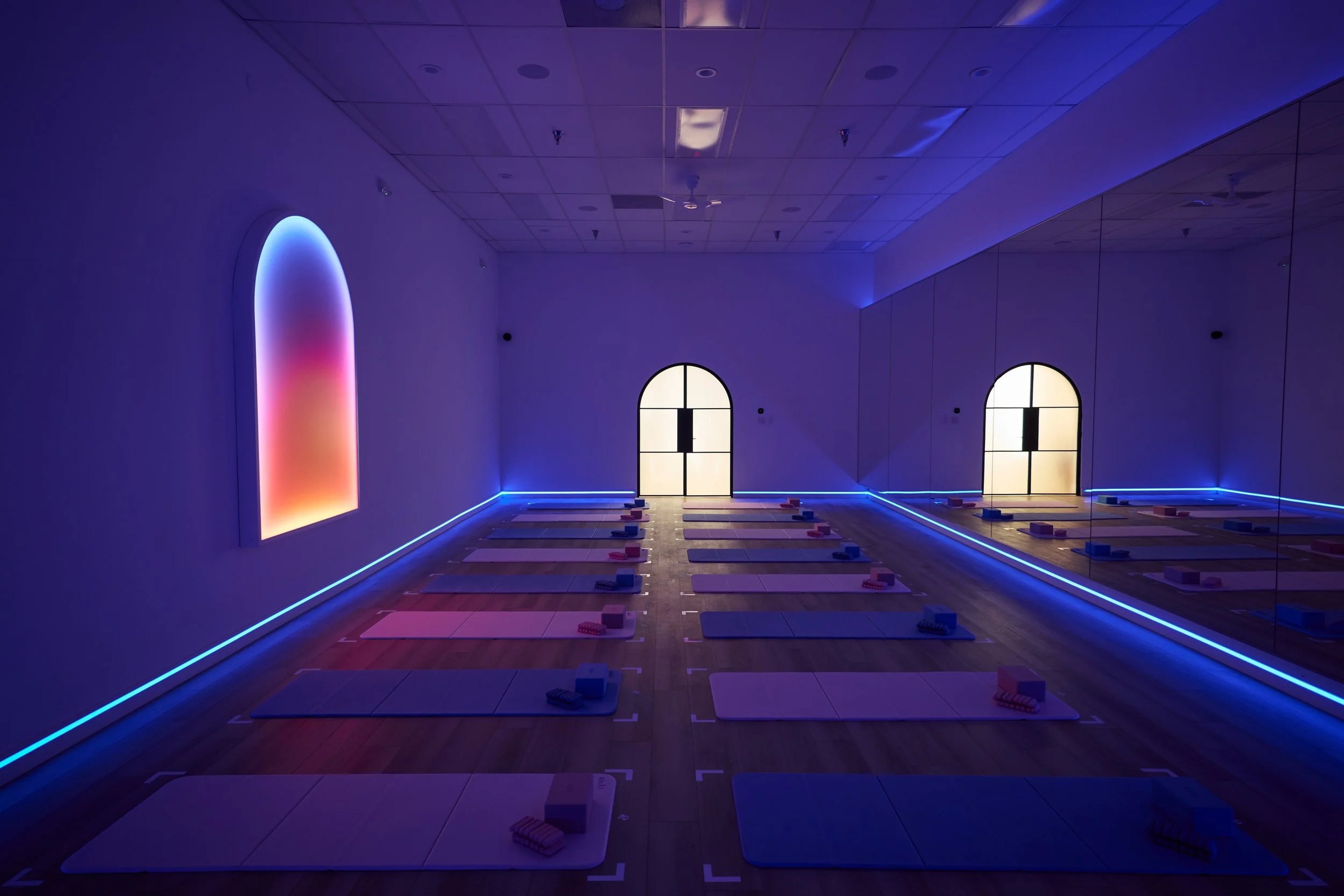 Mats arranged beneath arched lighting in the blue-lit Portal Pilates studio in Brickell.