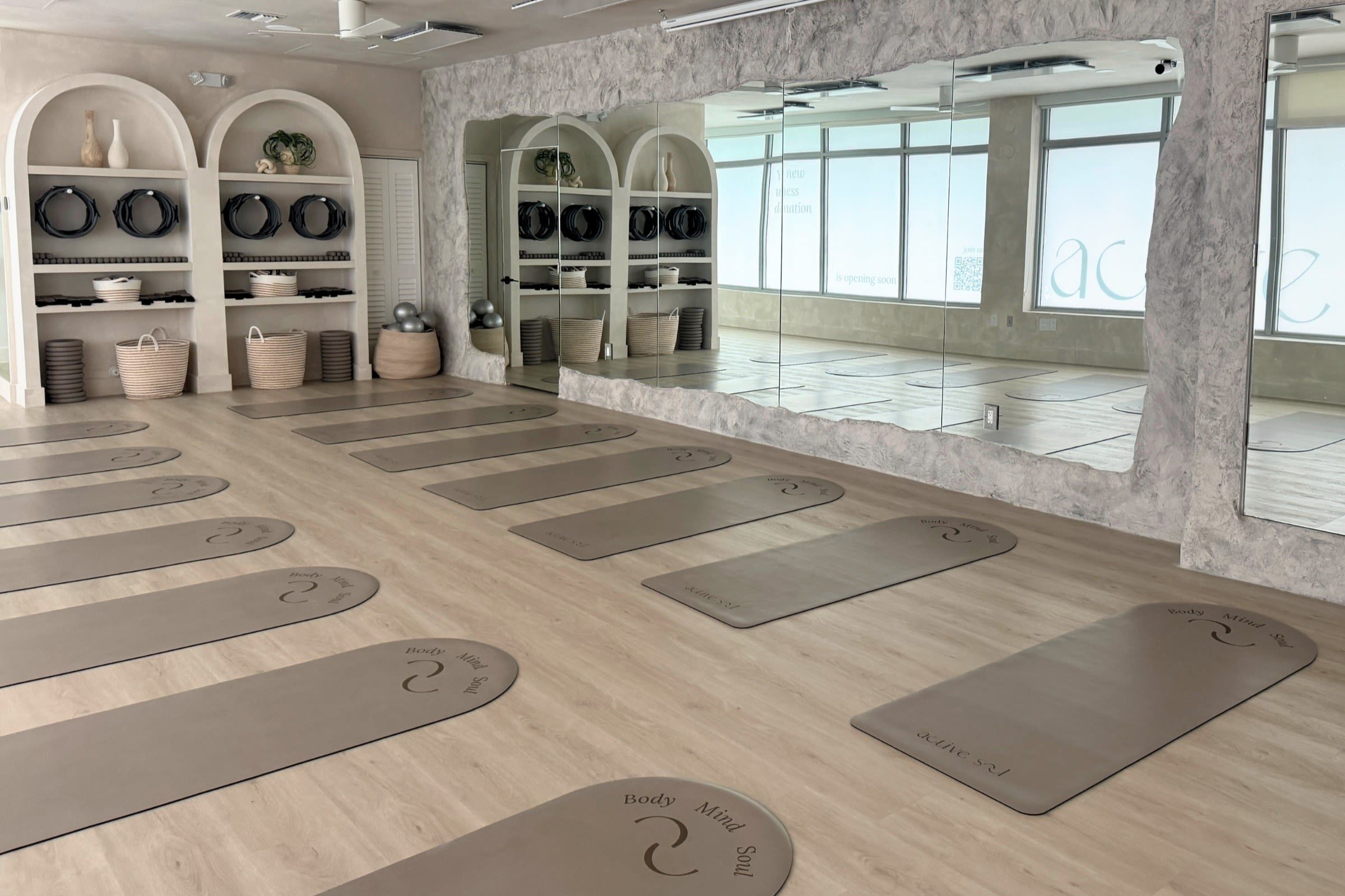 Mats arranged on pale wood floors beside sculptural shelves at ActiveSoul Wellness Studio