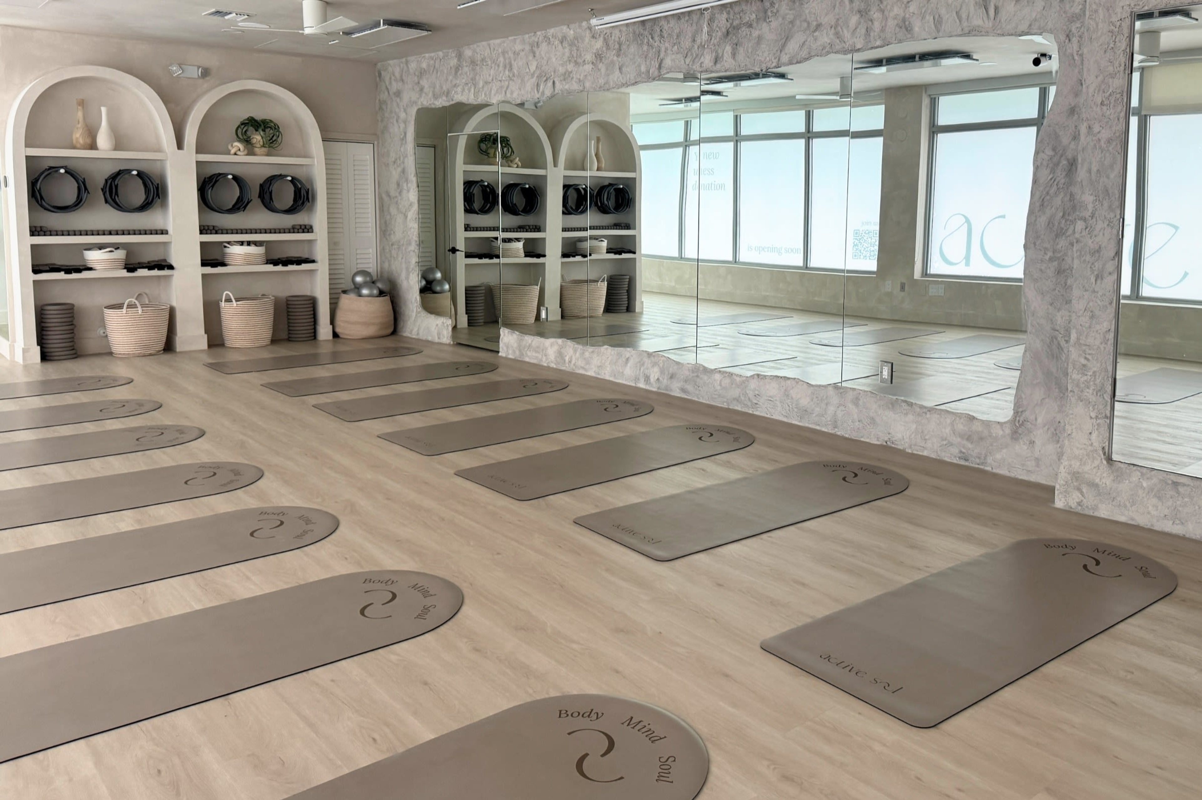 Mats arranged on pale wood floors beside sculptural shelves at ActiveSoul Wellness Studio