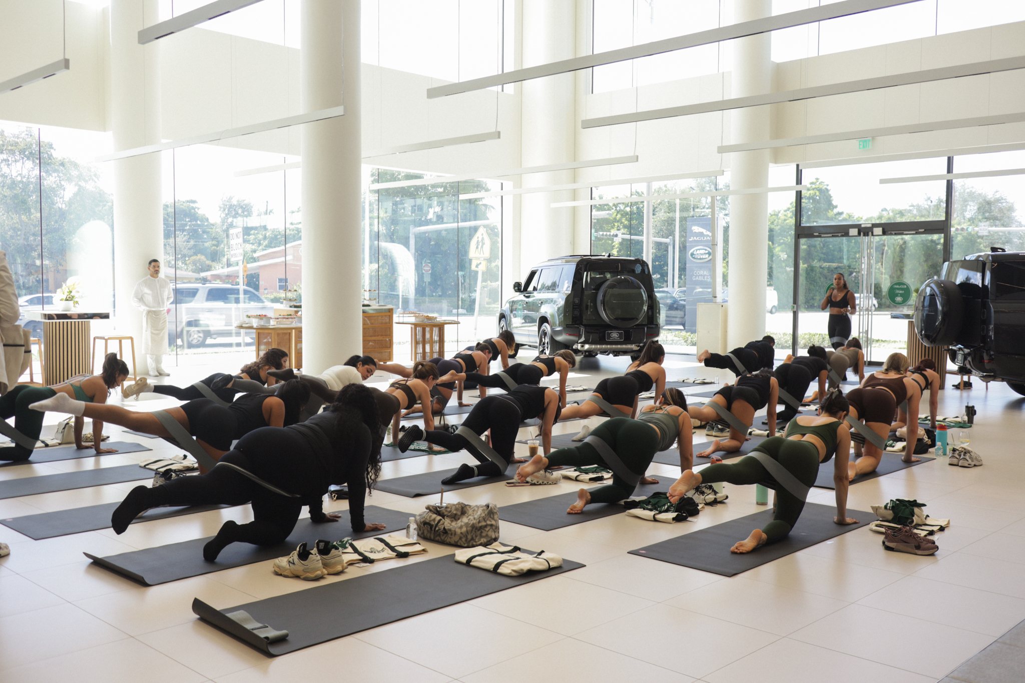Pilates class set up inside Land Rover Coral Gables showroom with Range Rover Sport in the background
