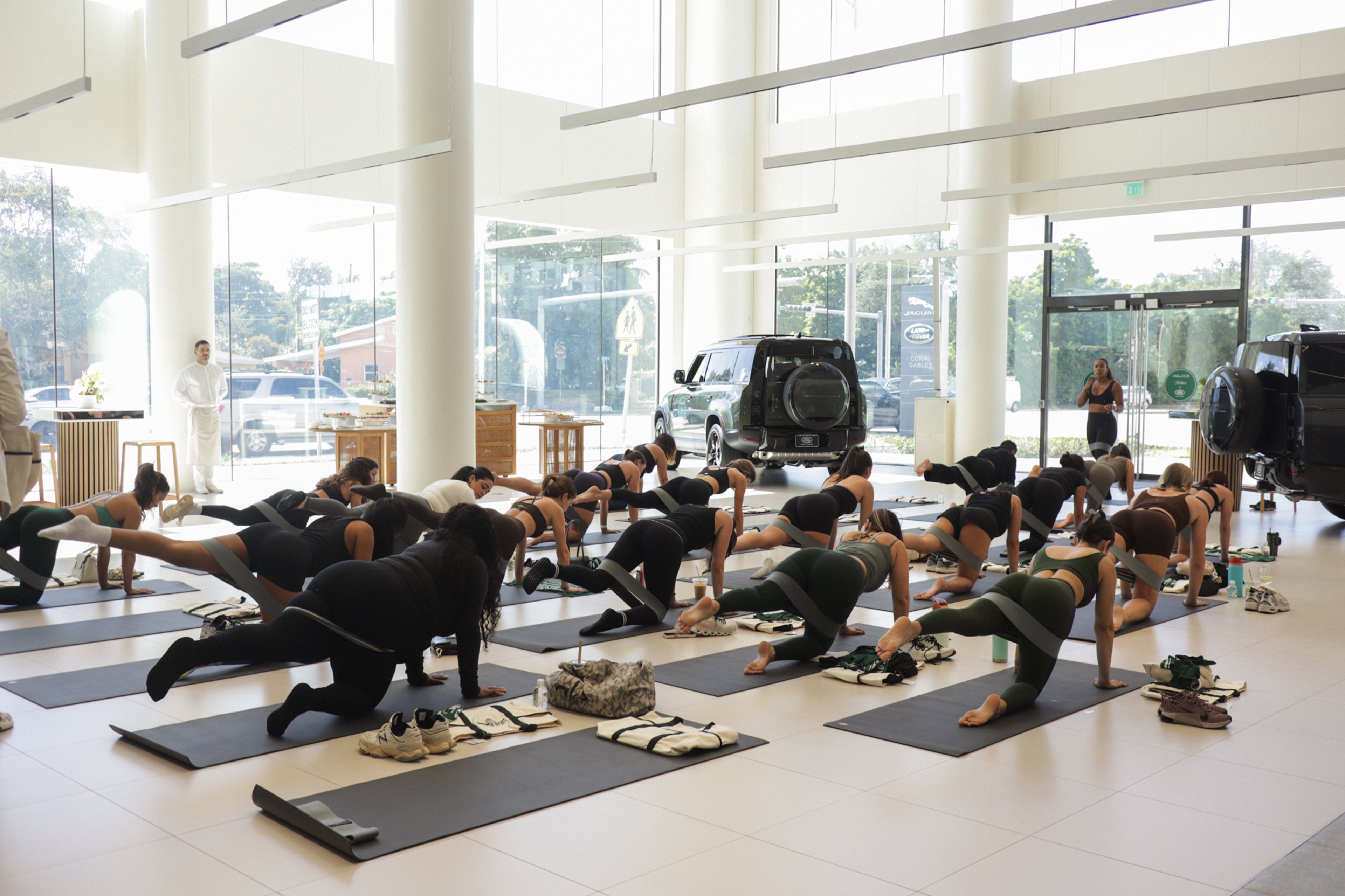 Pilates class set up inside Land Rover Coral Gables showroom with Range Rover Sport in the background
