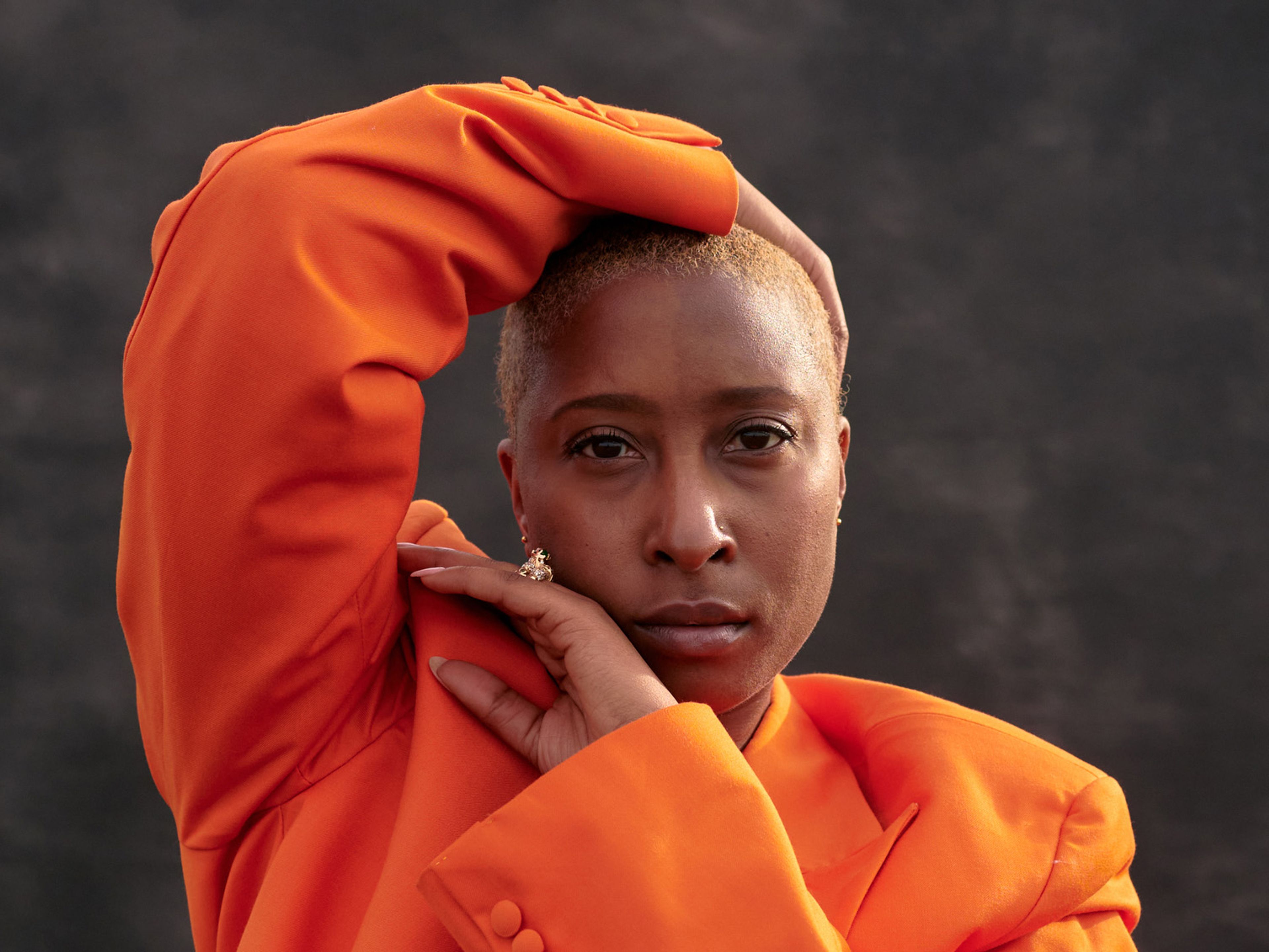 A woman in an orange jacket with her hands framing her head