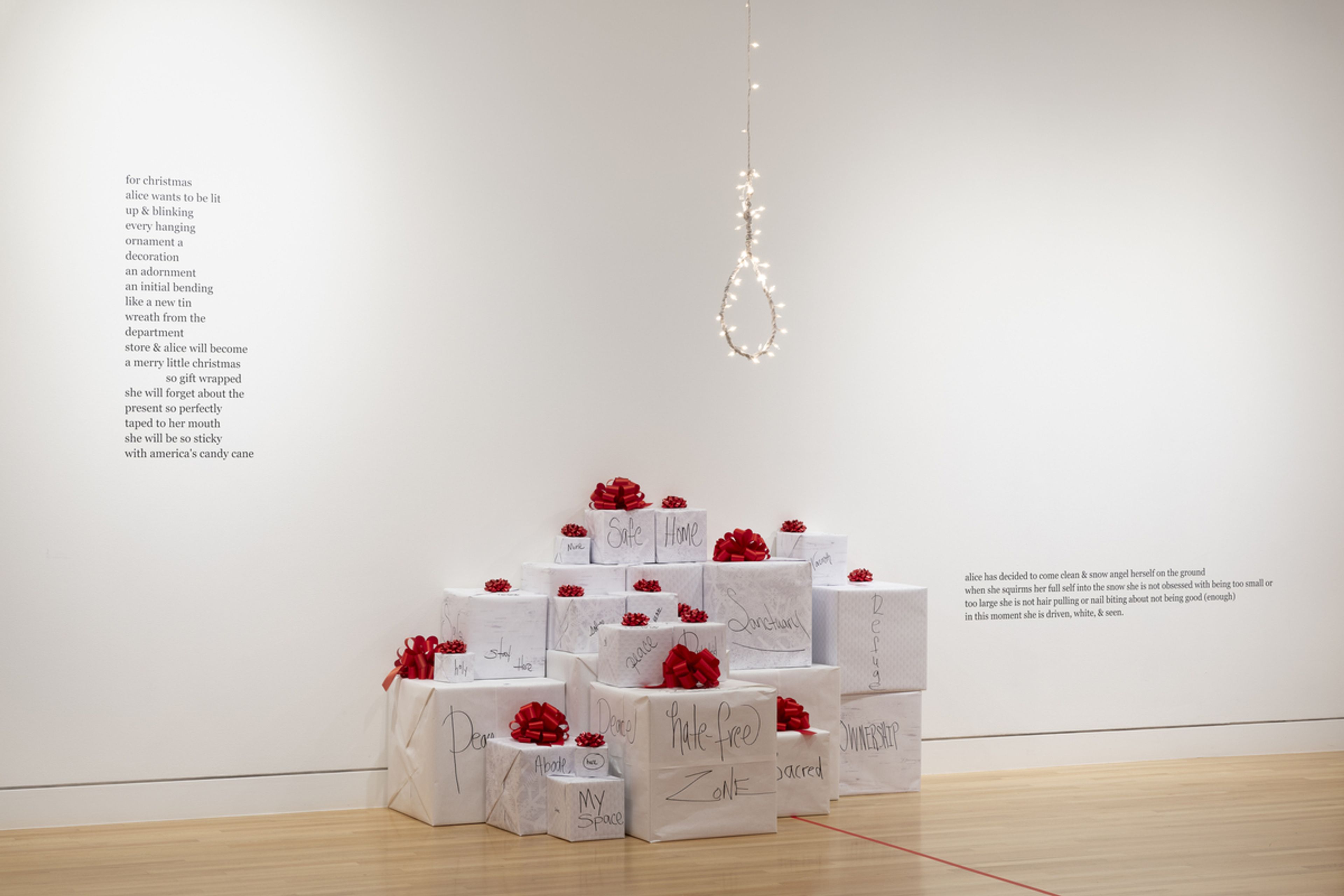 white boxes with red frills on top, a noose with string lights hangs above. A poem is written on the wall