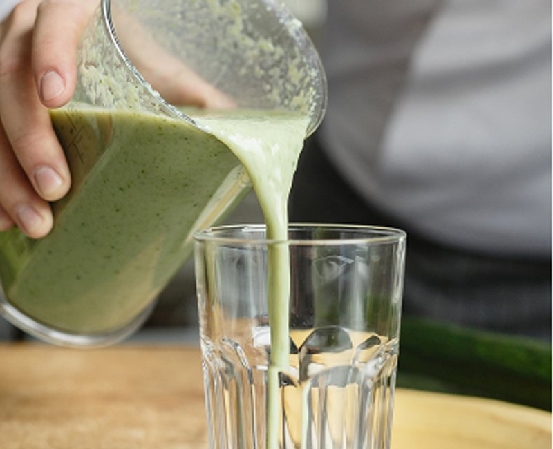 A green smoothie being poured into a glass