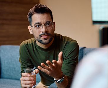 A man holding a glass of water during a conversation