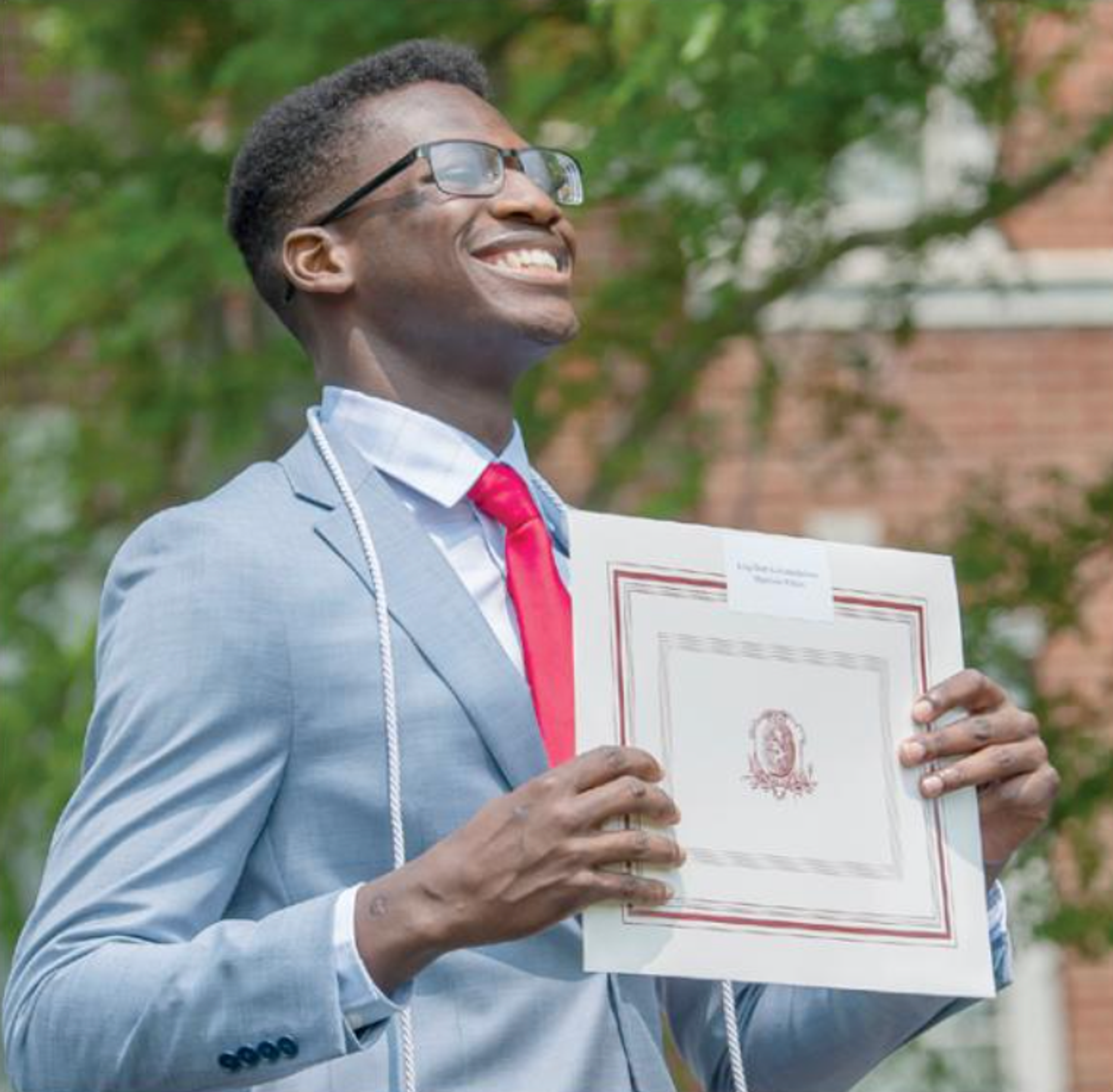 person smiling holding diploma