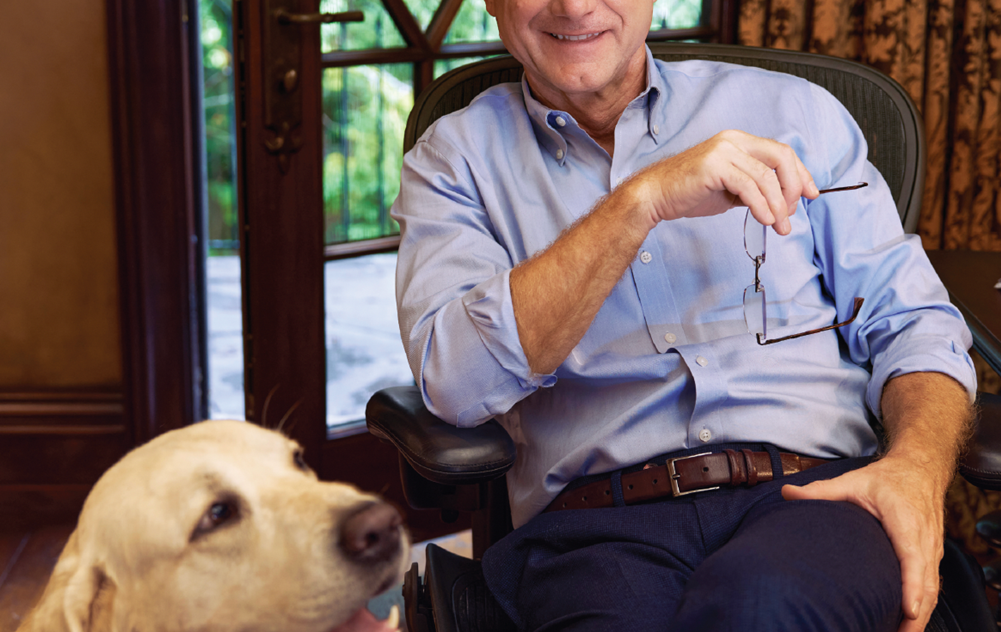 Man sitting down with a yellow lab next to him.