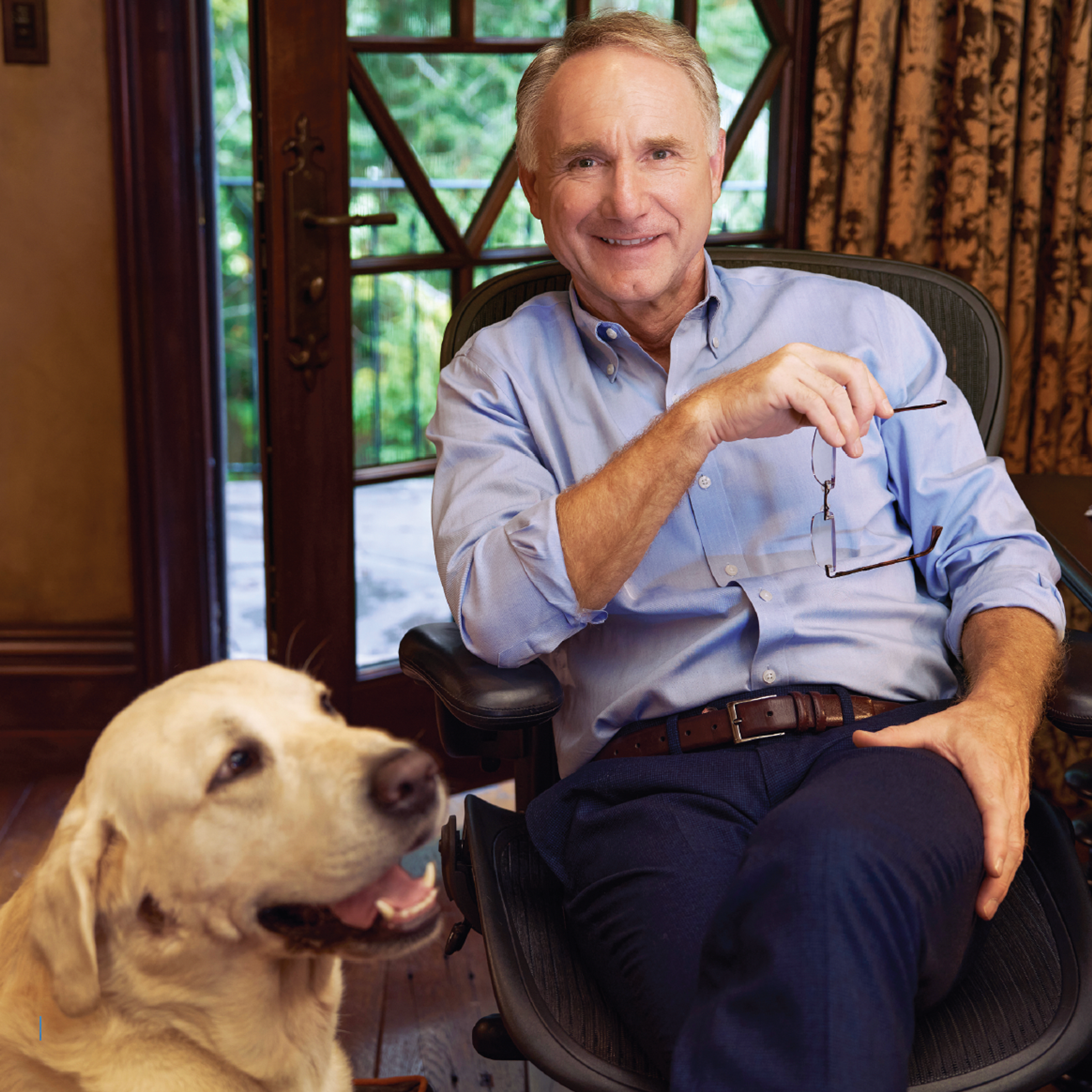 Man sitting down with a yellow lab next to him.