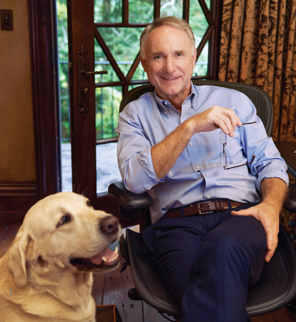 Man sitting down with a yellow lab next to him.